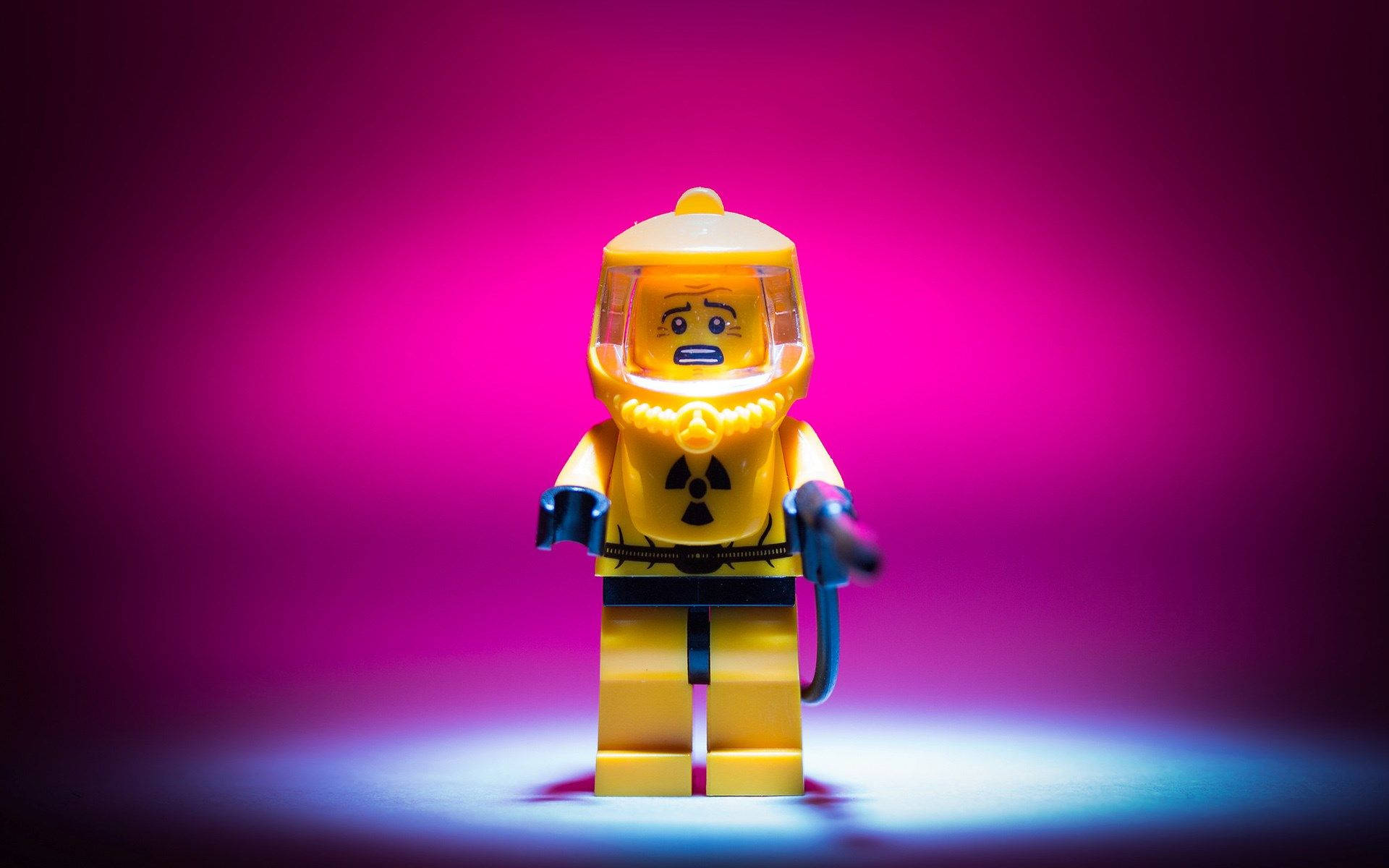 黃色LEGO人偶穿著防護衣在聚光燈下，洋紅色背景