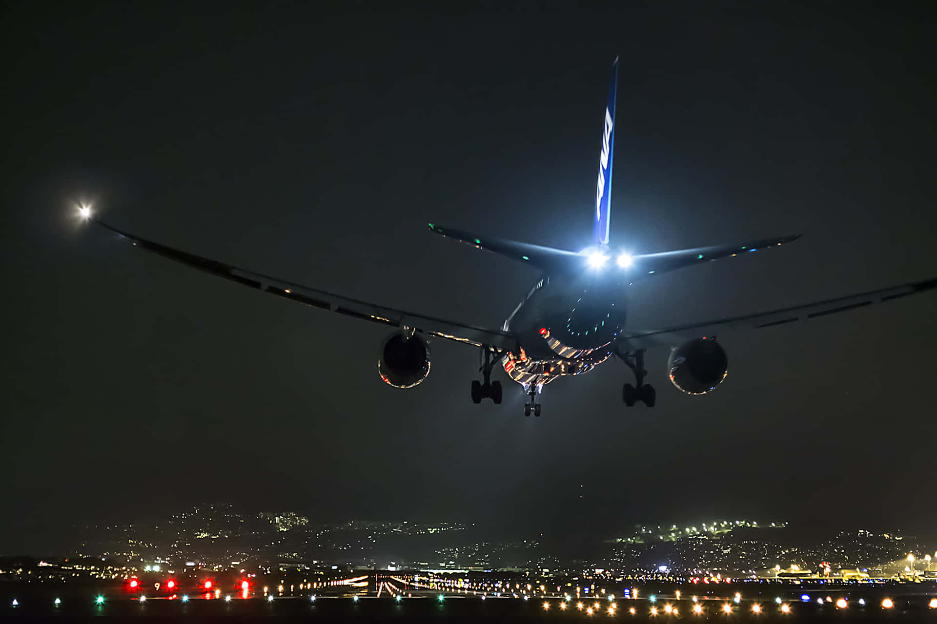 飛機夜間在城市上空降落，燈光璀璨。