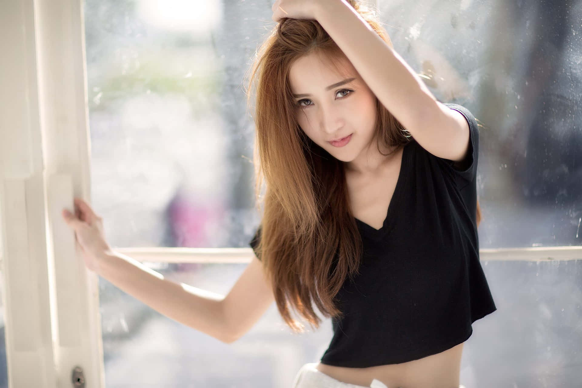 年輕女性穿黑色短版上衣倚靠雨窗