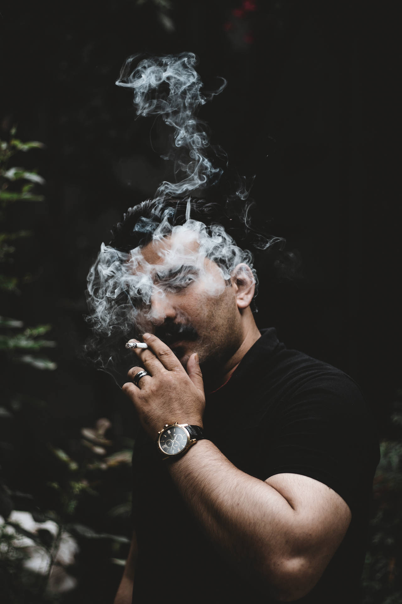 男人在黑暗森林中吸煙，煙霧在他臉龐周圍旋轉。