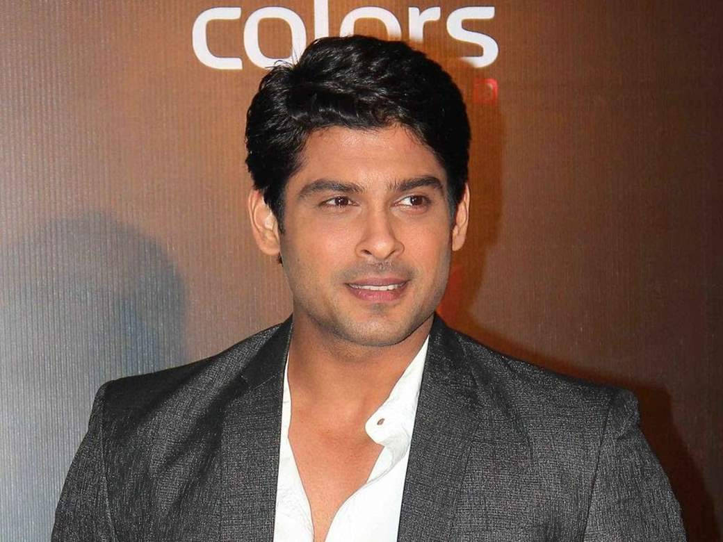 身穿灰色西裝和白色襯衫的男子在「colors」背景的活動中微笑。