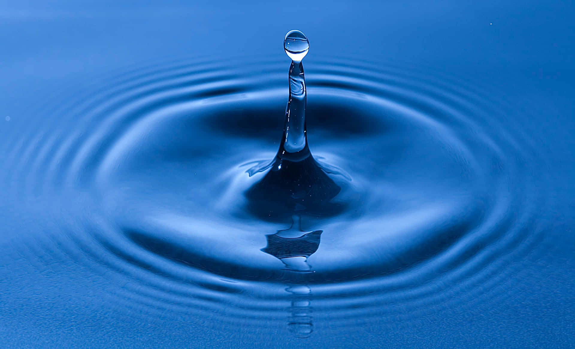 水滴皇冠喺藍色液體表面形成漣漪。
