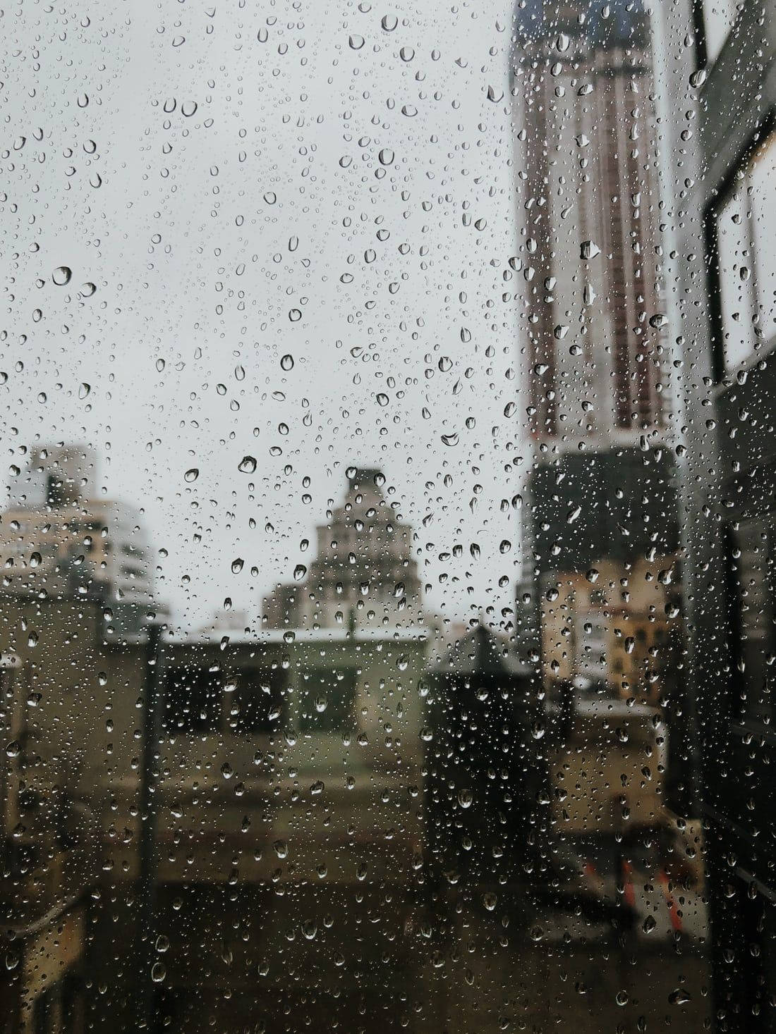 窗戶上的雨滴，背後是模糊的城市景色。