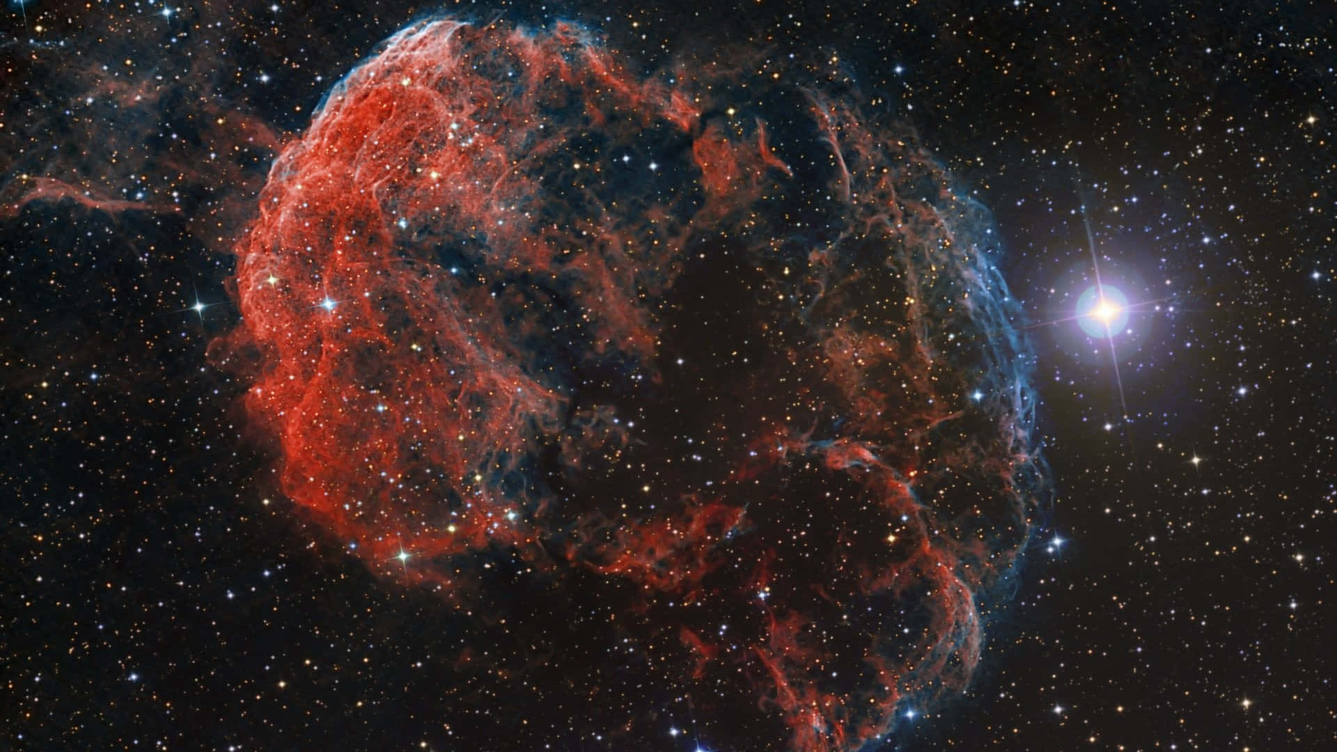 窺探外太空的奧秘 壁紙 — 一個充滿活力的紅色和藍色星雲在星空中旋轉，附近有一顆明亮的星星閃耀。