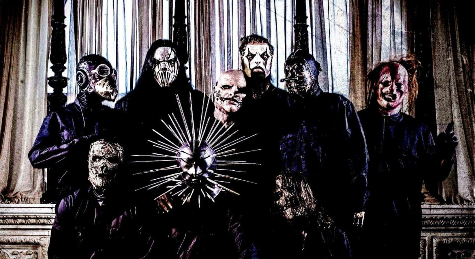 立即下載Slipknot桌面壁紙！ 壁紙 — 七個戴面具、身穿深色長袍的人物站在華麗的窗簾前，中央有一個帶尖刺的金屬頭骨。