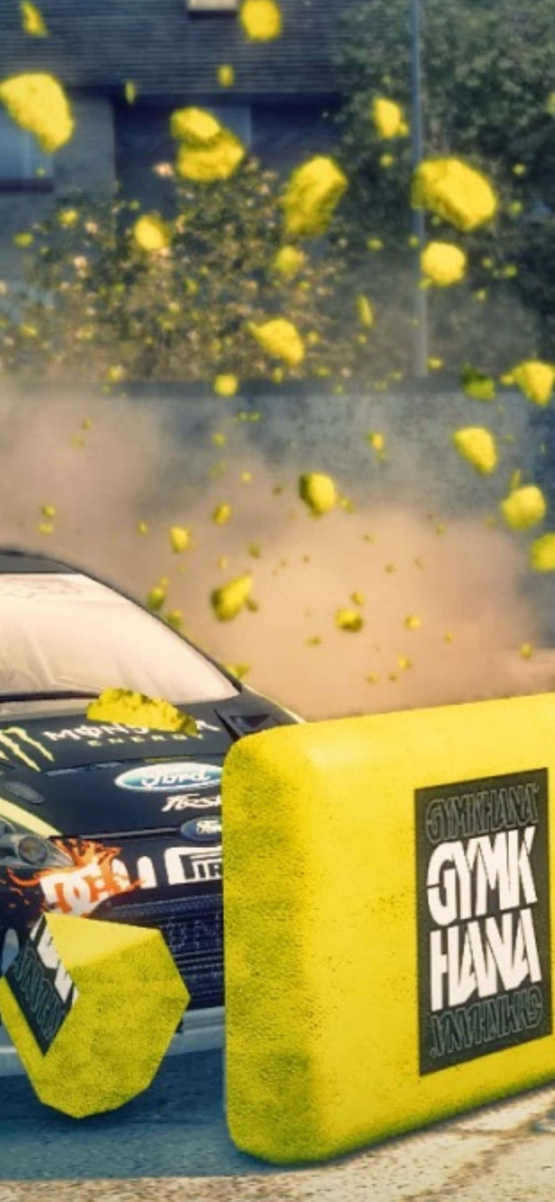 立即擁有最新 iPhone XS《Dirt 3》專屬外殼 壁紙 — 一輛拉力賽車撞上黃色方塊，碎片在粗糙的城市環境中飛散。