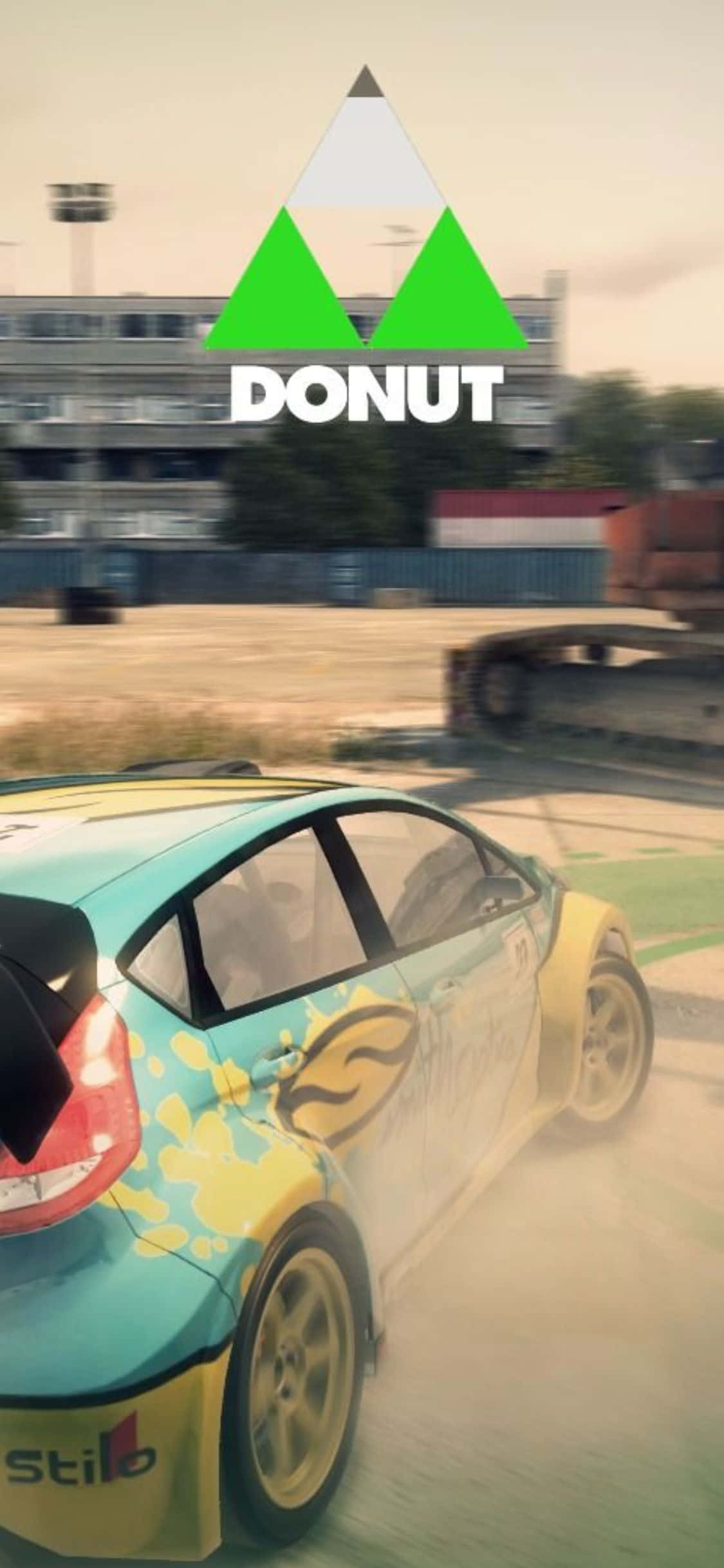 立即擁有最新 iPhone XS 與《Dirt 3》遊戲應用！ 壁紙 — 一輛色彩繽紛的拉力賽車在塵土飛揚的賽道上飄移，上方有「DONUT」標誌的電玩場景。