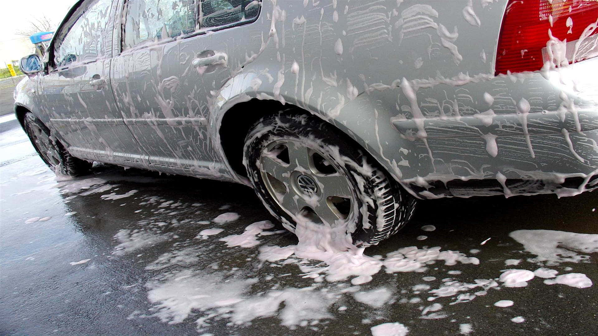 戶外洗車時被肥皂泡覆蓋的銀色汽車