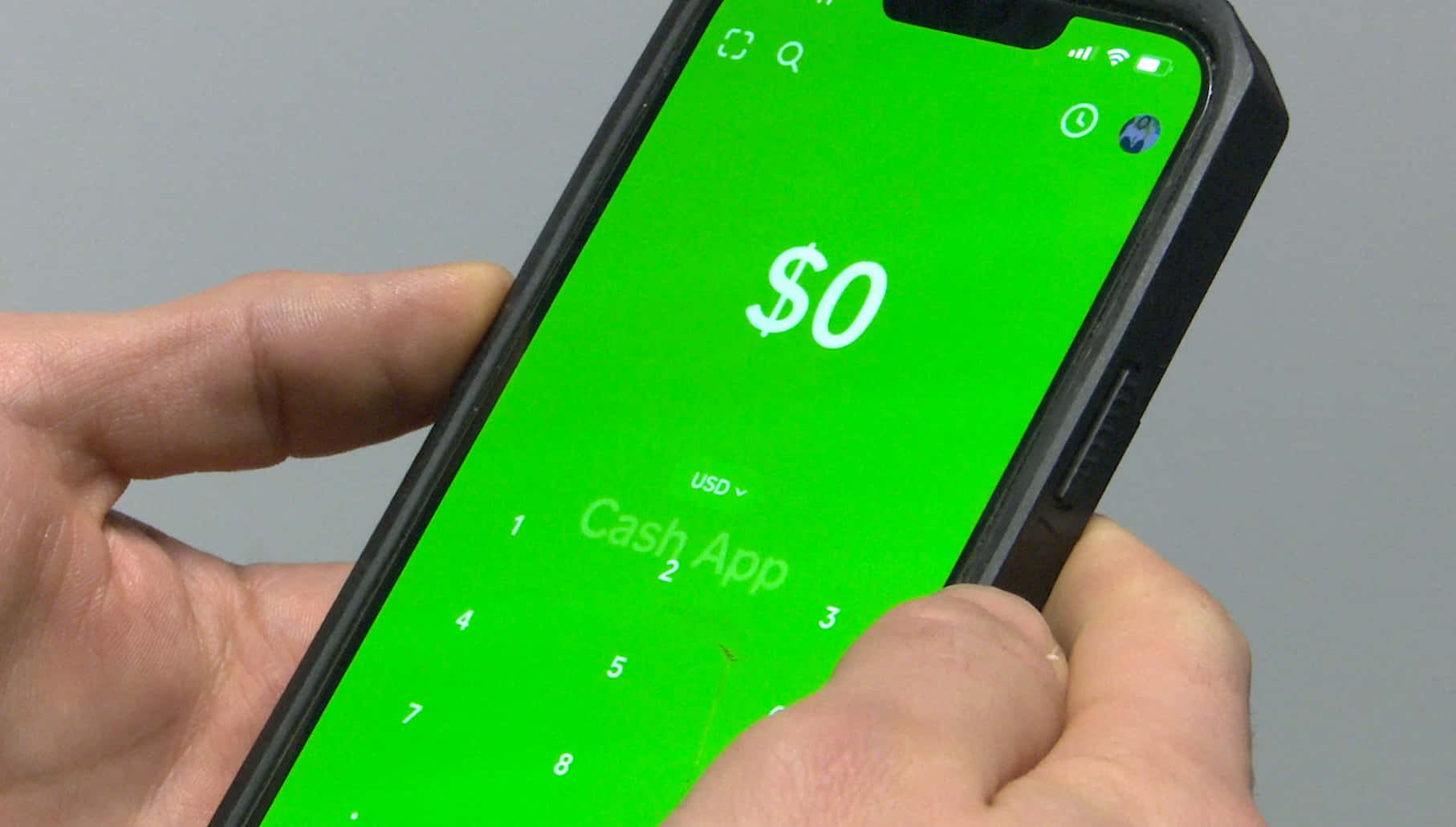 手拿著手機，Cash App 顯示餘額為零。