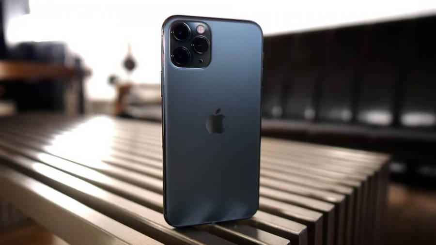 立式 iPhone 11 Pro 壁紙 — 一部纖薄的藍色 iPhone 12 Pro Max 直立於金屬條紋長凳上，背景柔和模糊。