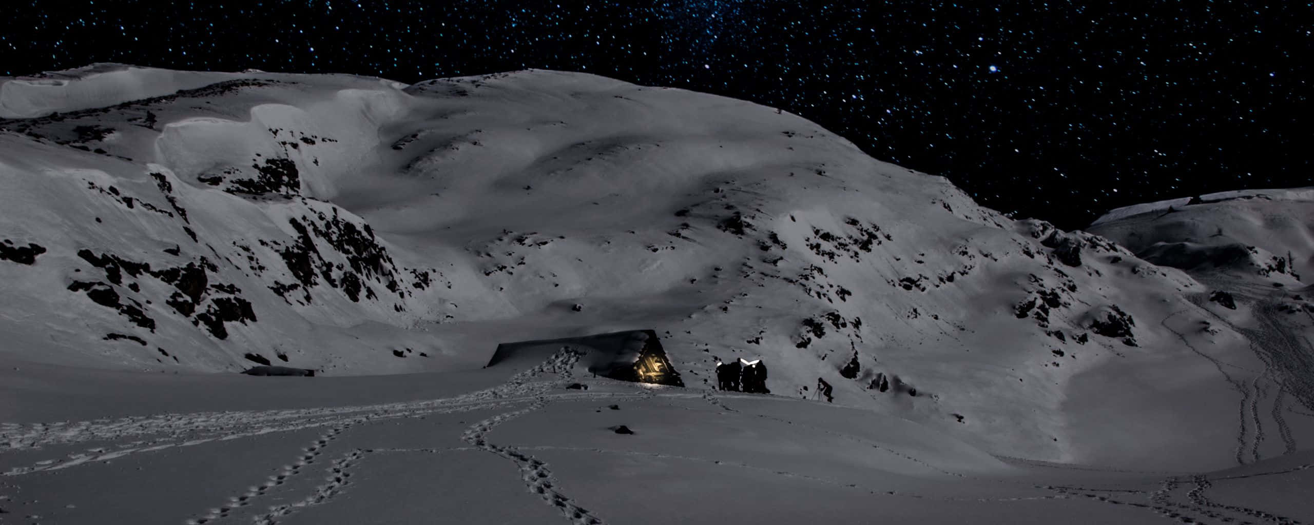 星空下溫暖發光且有腳印的積雪山洞