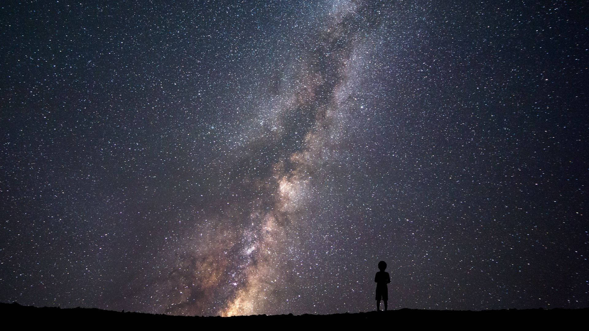 一個人獨自站在星空下，銀河系清晰可見。