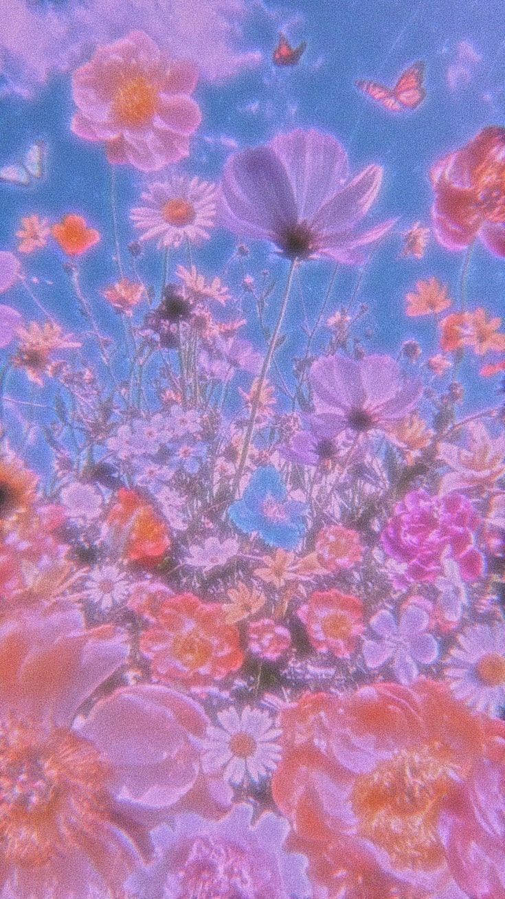 藍天下夢幻花田中鮮豔的柔和色調花朵和蝴蝶。