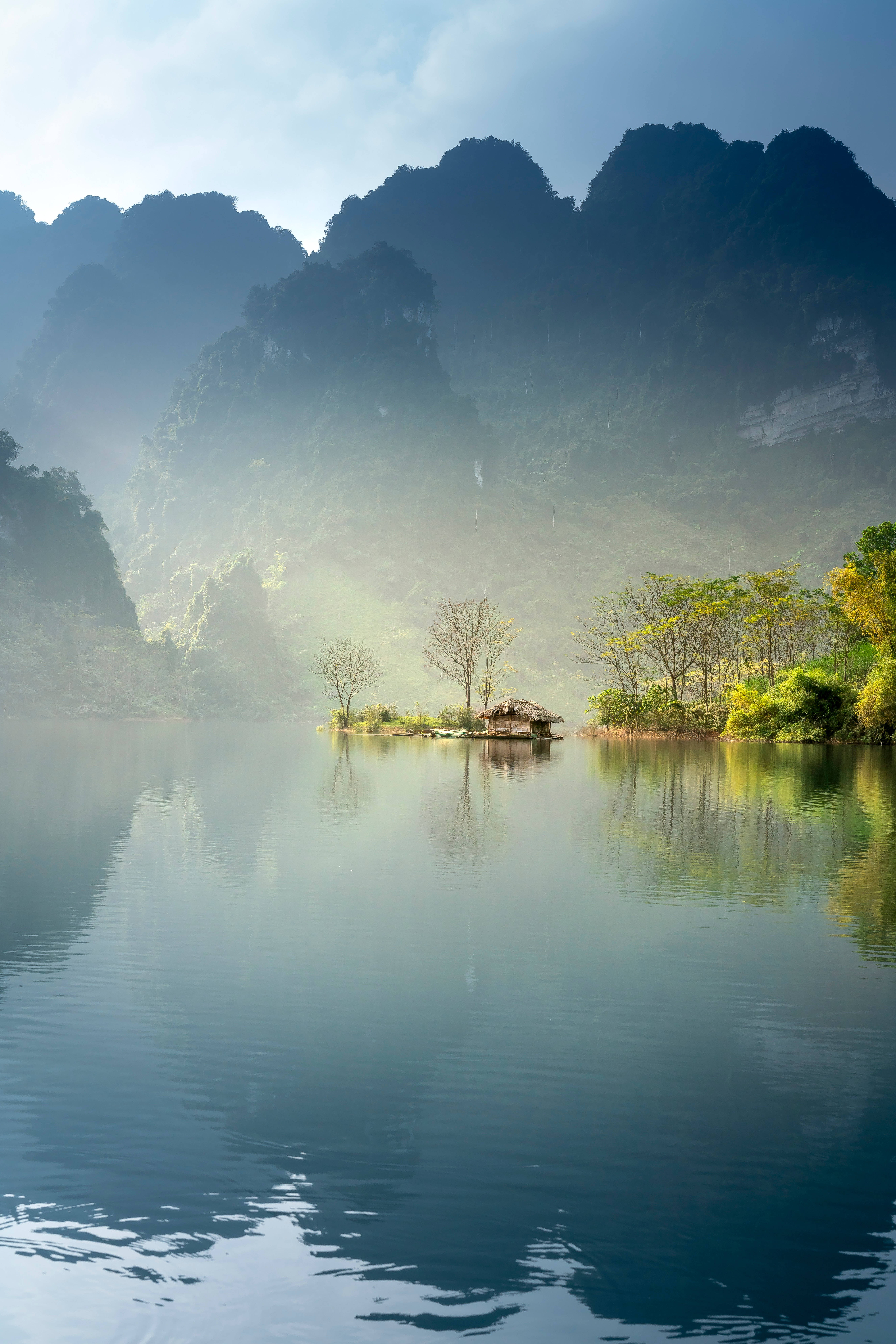 竹屋河景 壁紙 — 霧氣瀰漫的黎明，寧靜的湖面上，一個小島上孤零零的木屋，四周是高聳的喀斯特山峰。