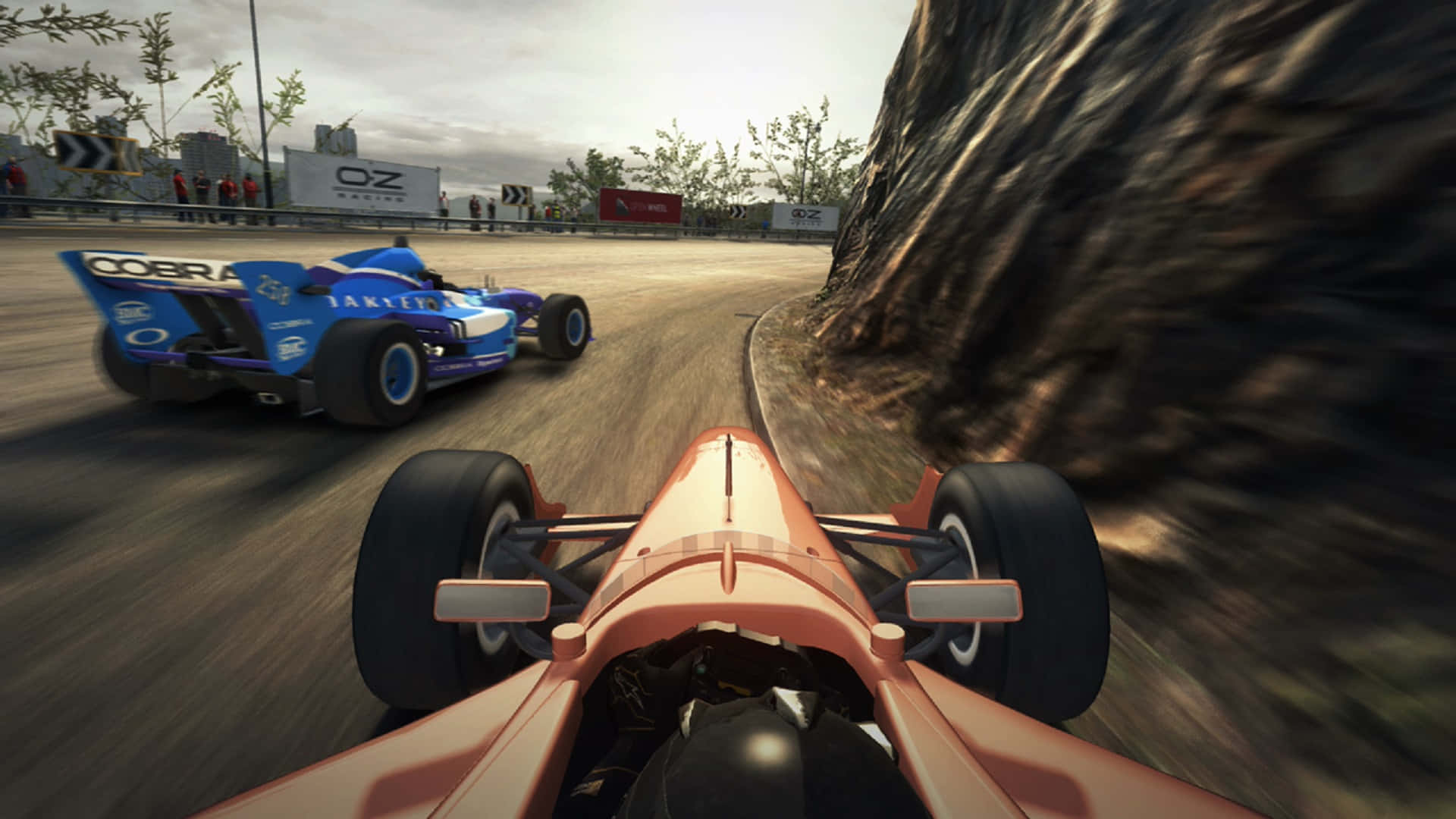 Grid Autosport 桌布 壁紙 — 第一人稱視角，一輛珊瑚色賽車在岩石懸崖旁的蜿蜒賽道上超越藍色對手。