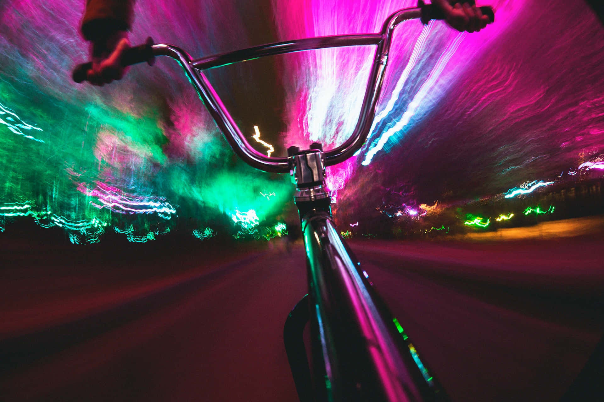 Psychedelic Neon Lights 桌布 壁紙 — 第一人稱視角，單車在霓虹燈閃爍的都市夜晚中疾馳，帶有粉紅、綠色和藍色的光條。