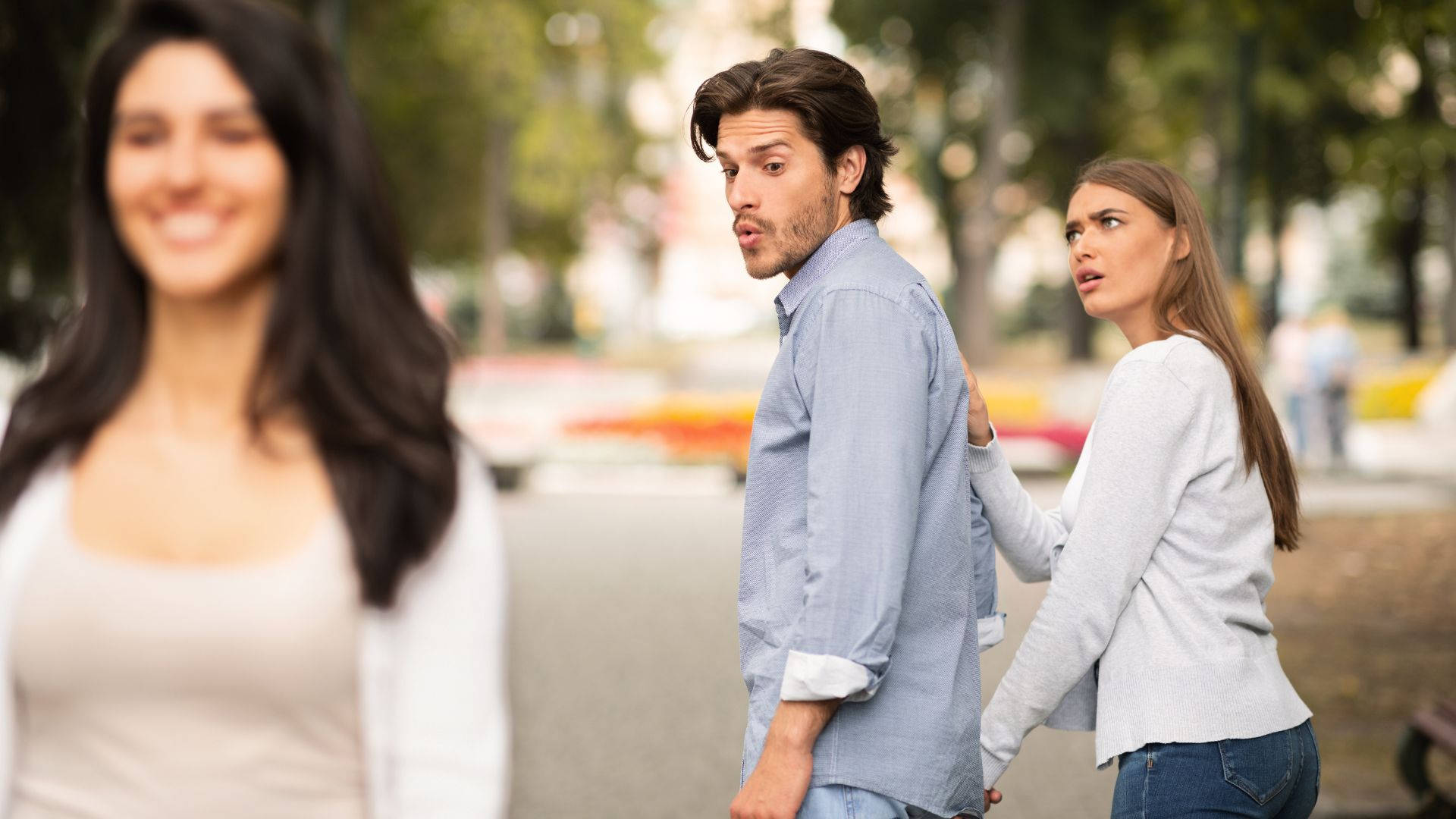 男人看起來很驚訝，一個女人摸他的背，而另一個女人在附近微笑。