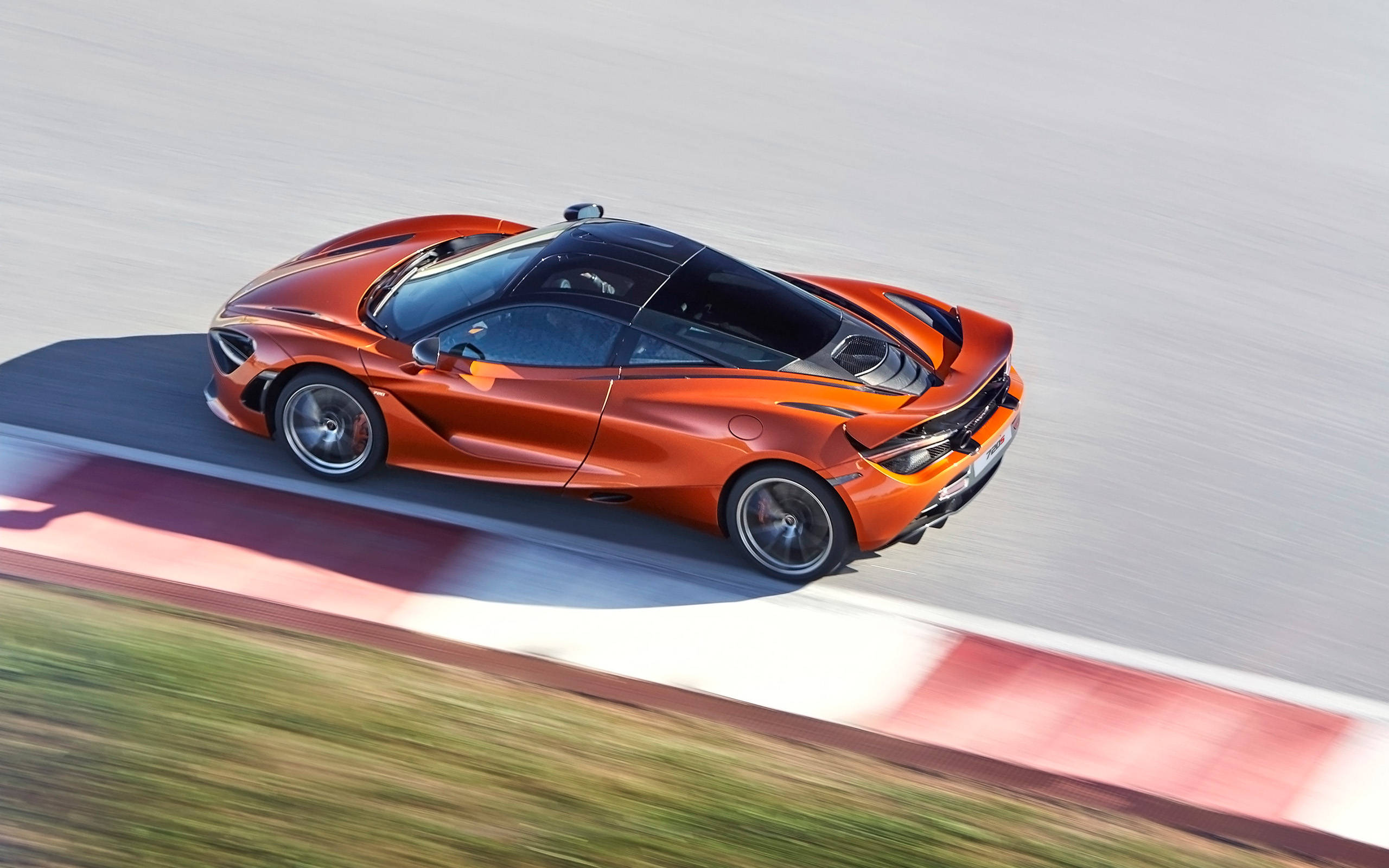 第二代麥拉倫720s 4K 壁紙 — 一輛充滿活力的橙色McLaren跑車在賽道上疾馳，動態模糊強調其高速。