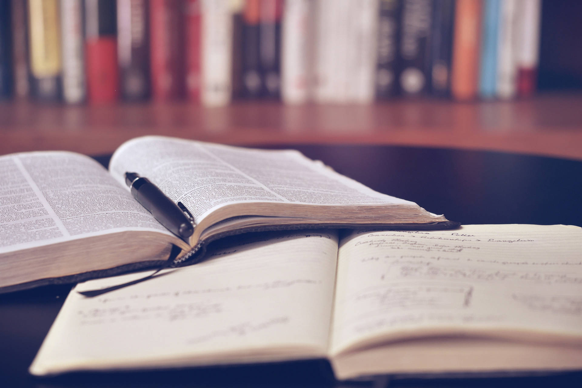 打開的字典和筆記本，筆放在書架附近的桌子上。
