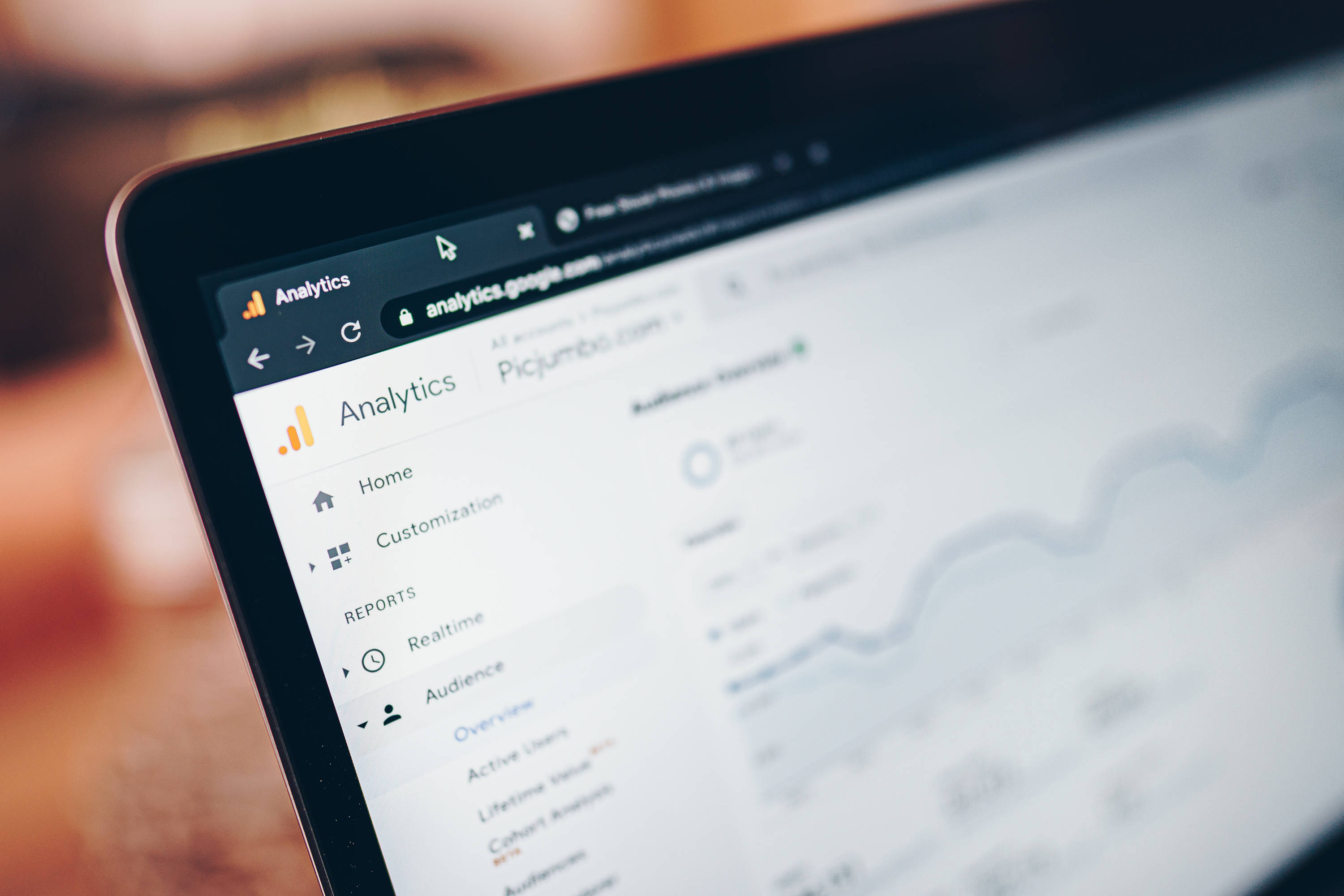 筆記本電腦顯示Google Analytics網站 壁紙 — 手提電腦屏幕特寫，顯示Google Analytics儀表板，背景模糊。
