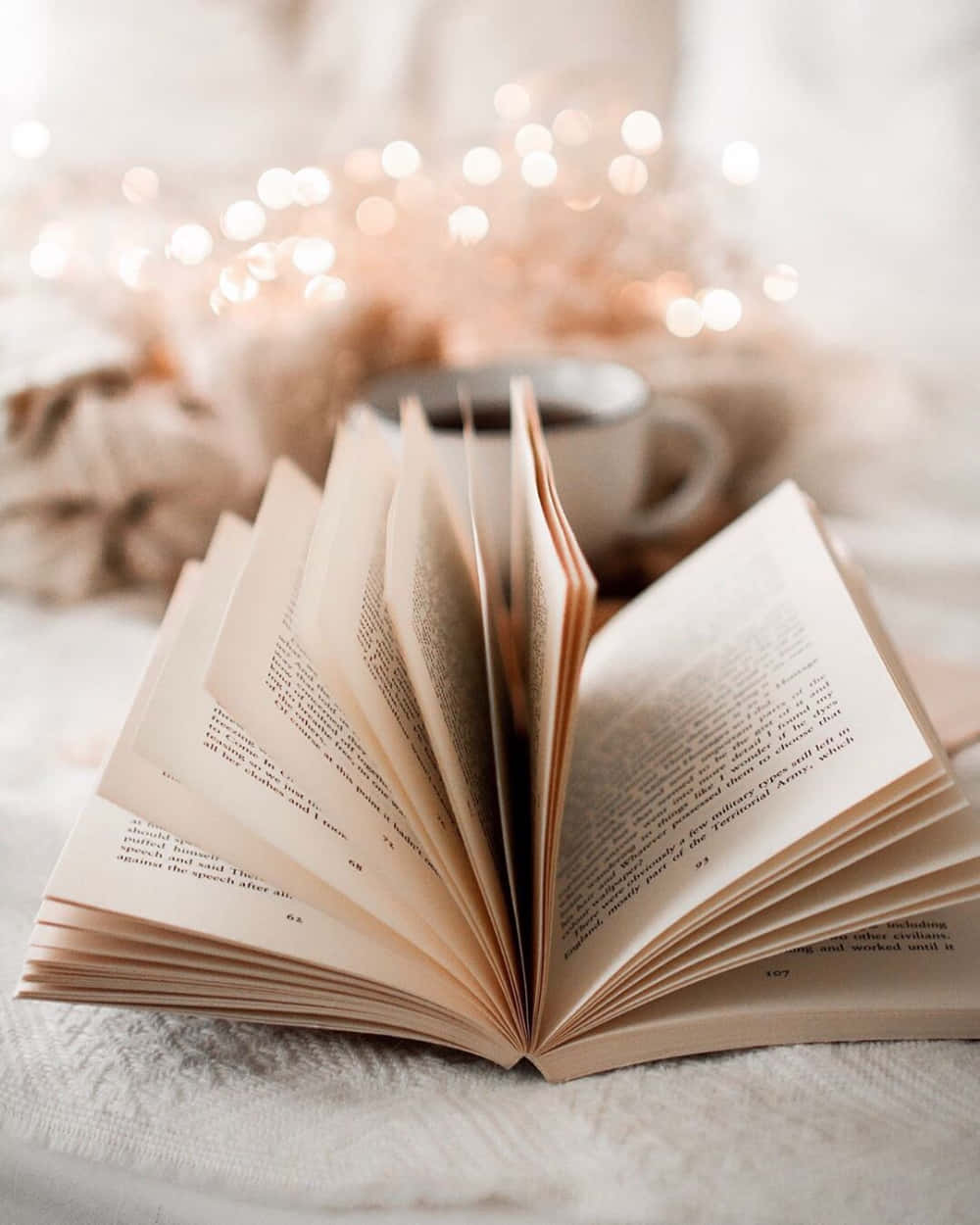 打開的書、杯子和仙女燈，營造舒適的閱讀氛圍。