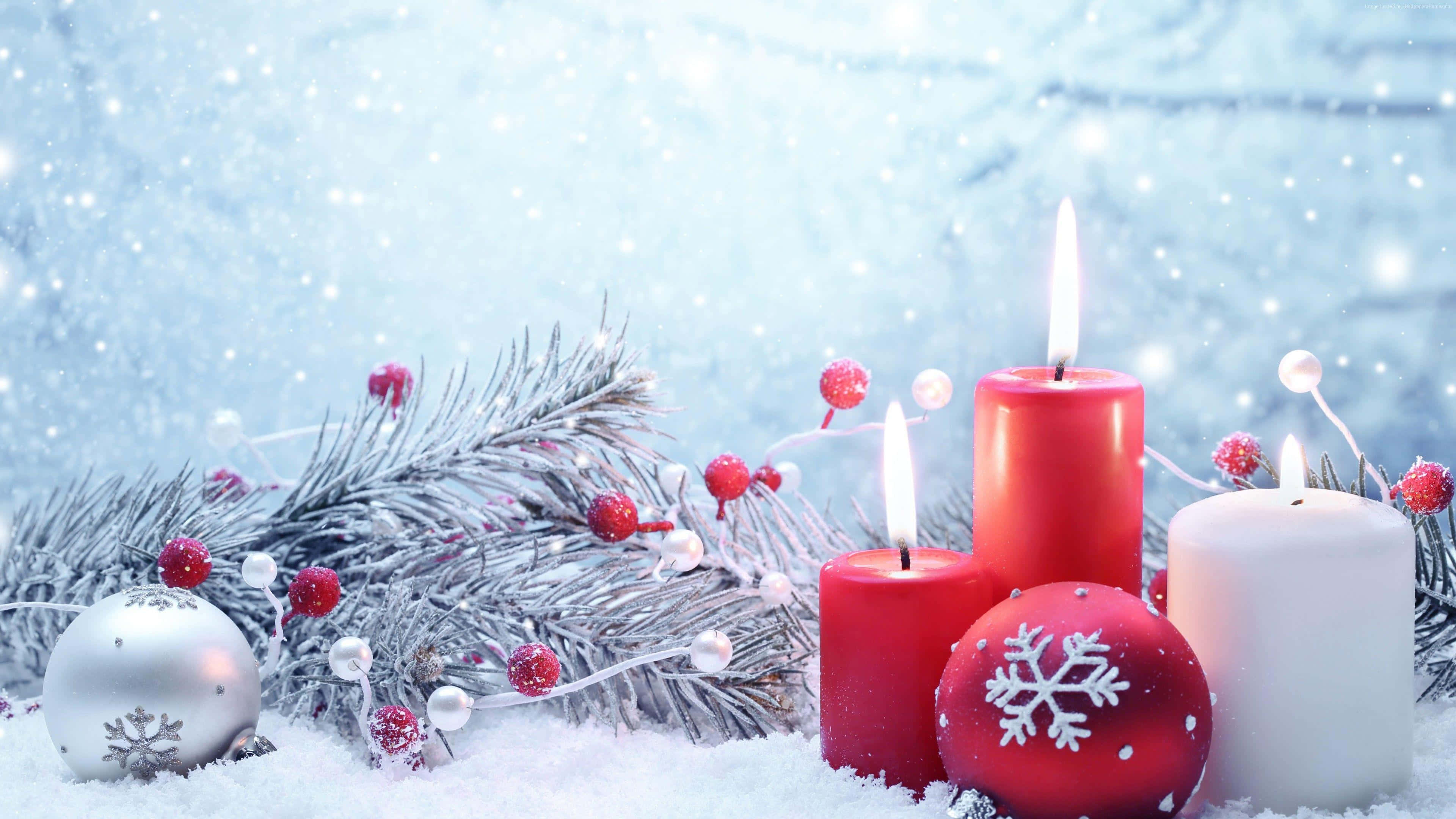 Rustic Christmas 桌布 壁紙 — 節日冬季場景，有發光的蠟燭、紅色和白色的裝飾品以及雪花覆蓋的松樹枝，在飄落的雪花下。