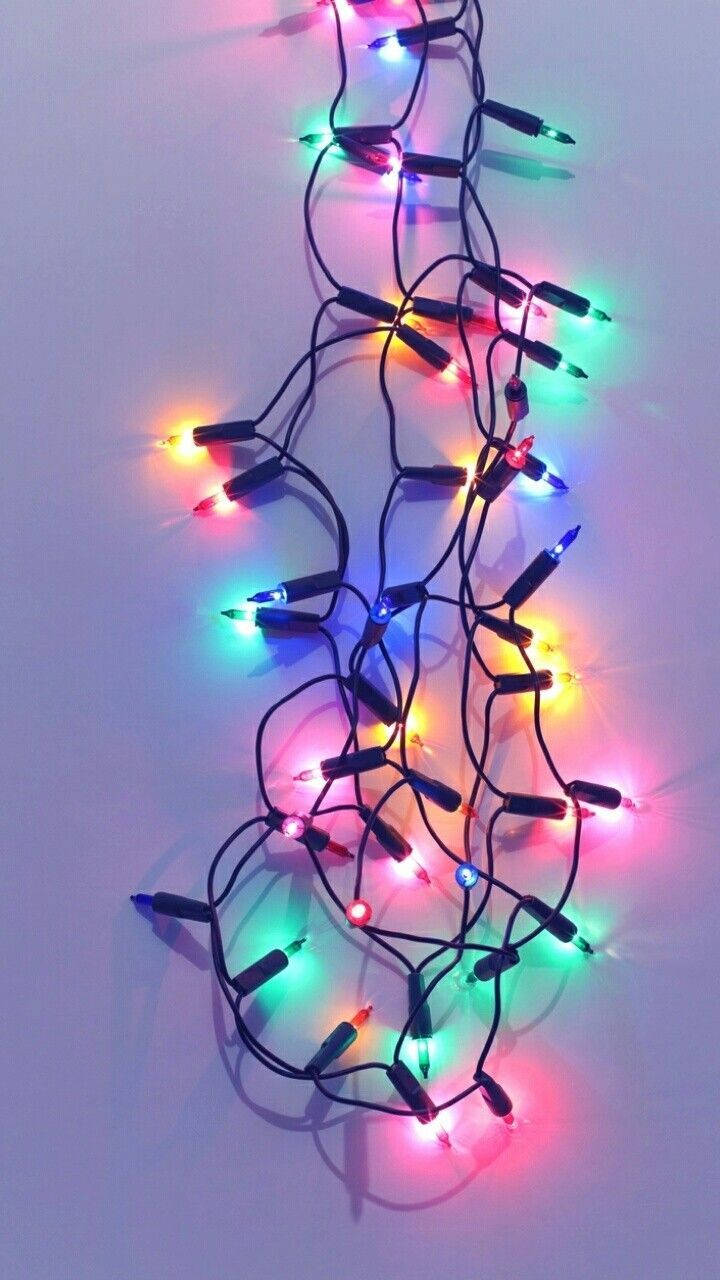 纏繞著的彩色發光LED燈串在灰色表面上。