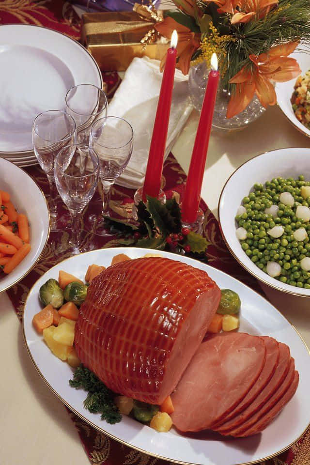 Black Forest Ham 桌布 壁紙 — 節日餐桌中心裝飾，以切片蜜汁火腿為主角，周圍環繞蔬菜和紅色蠟燭。