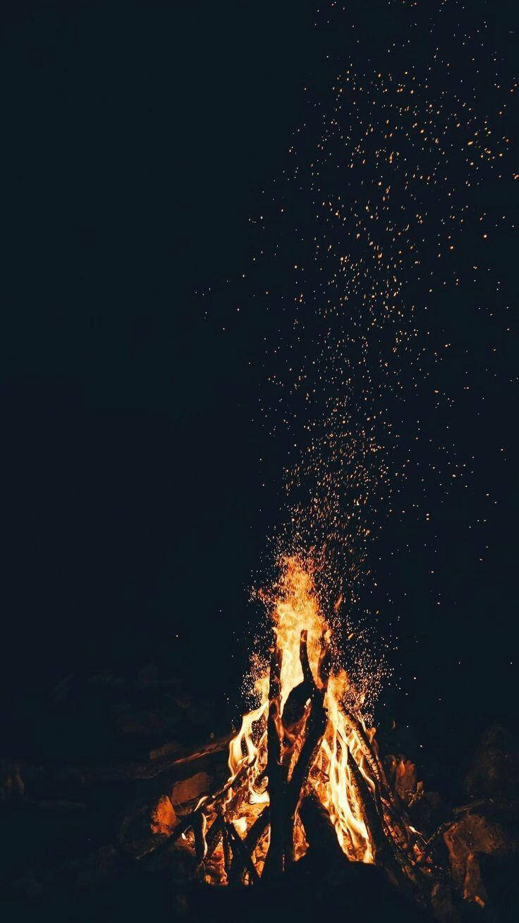 營火發光，火花升入黑暗的夜空