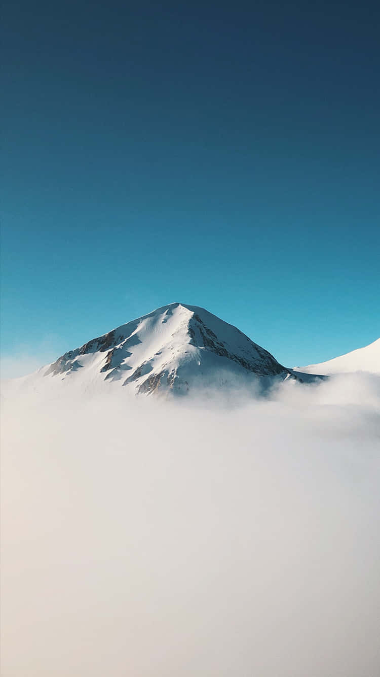 在蔚藍天空下，白雪覆蓋的山峰從雲層中浮現