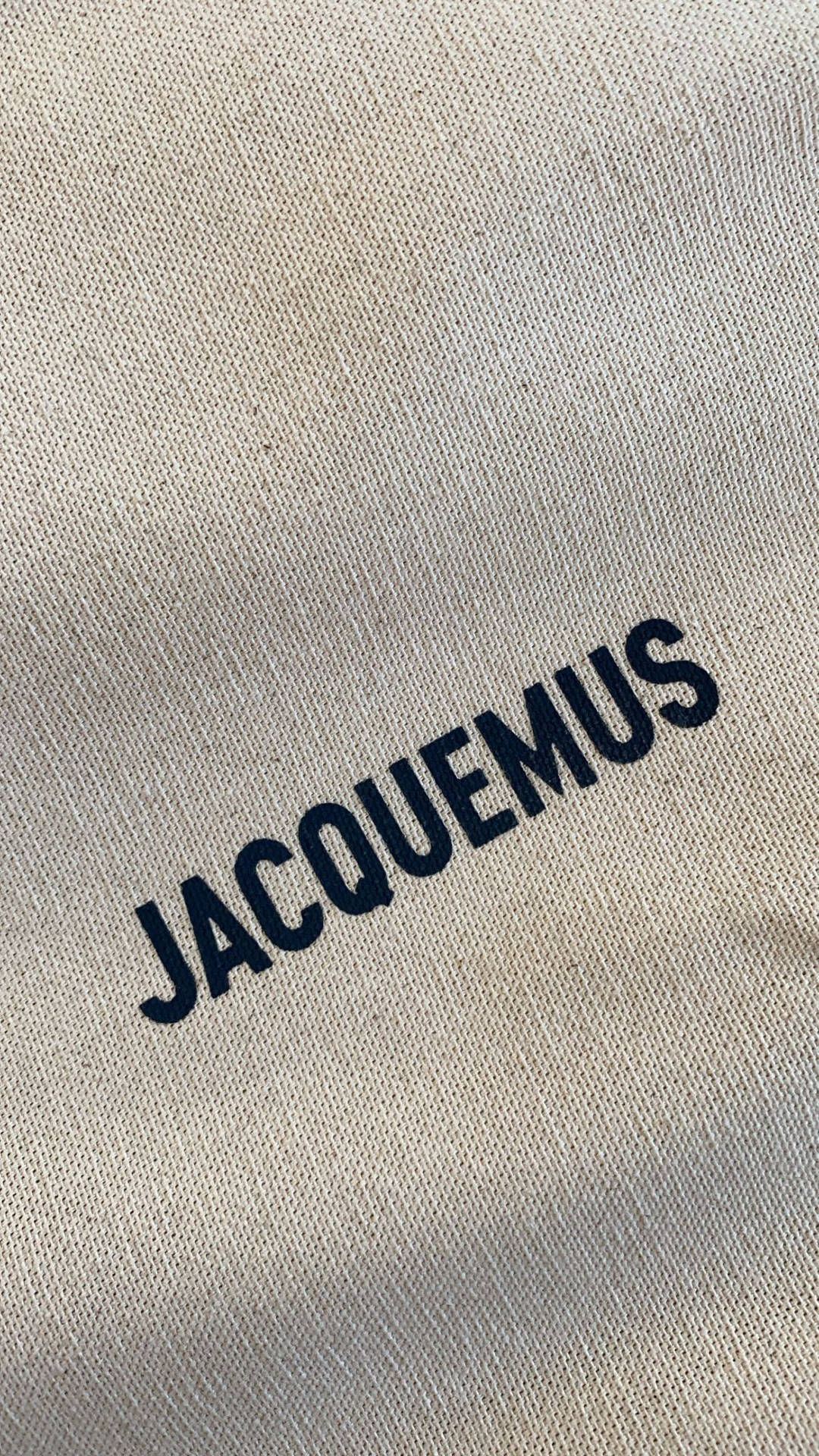 米色布料上以粗體刺繡的海軍藍 JACQUEMUS 標誌。