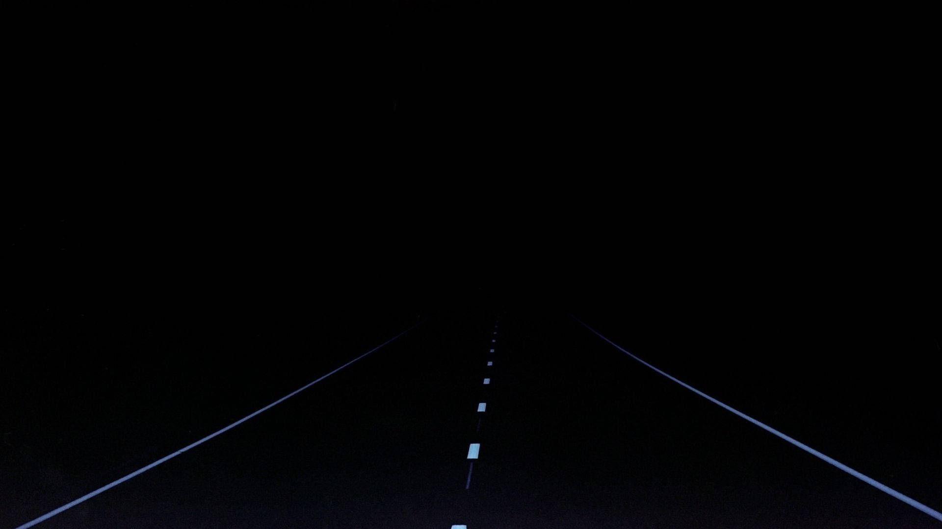 簡約暗色道路 壁紙 — 一條孤獨的道路在夜間延伸至黑暗，僅由發光的白色車道標記照亮。