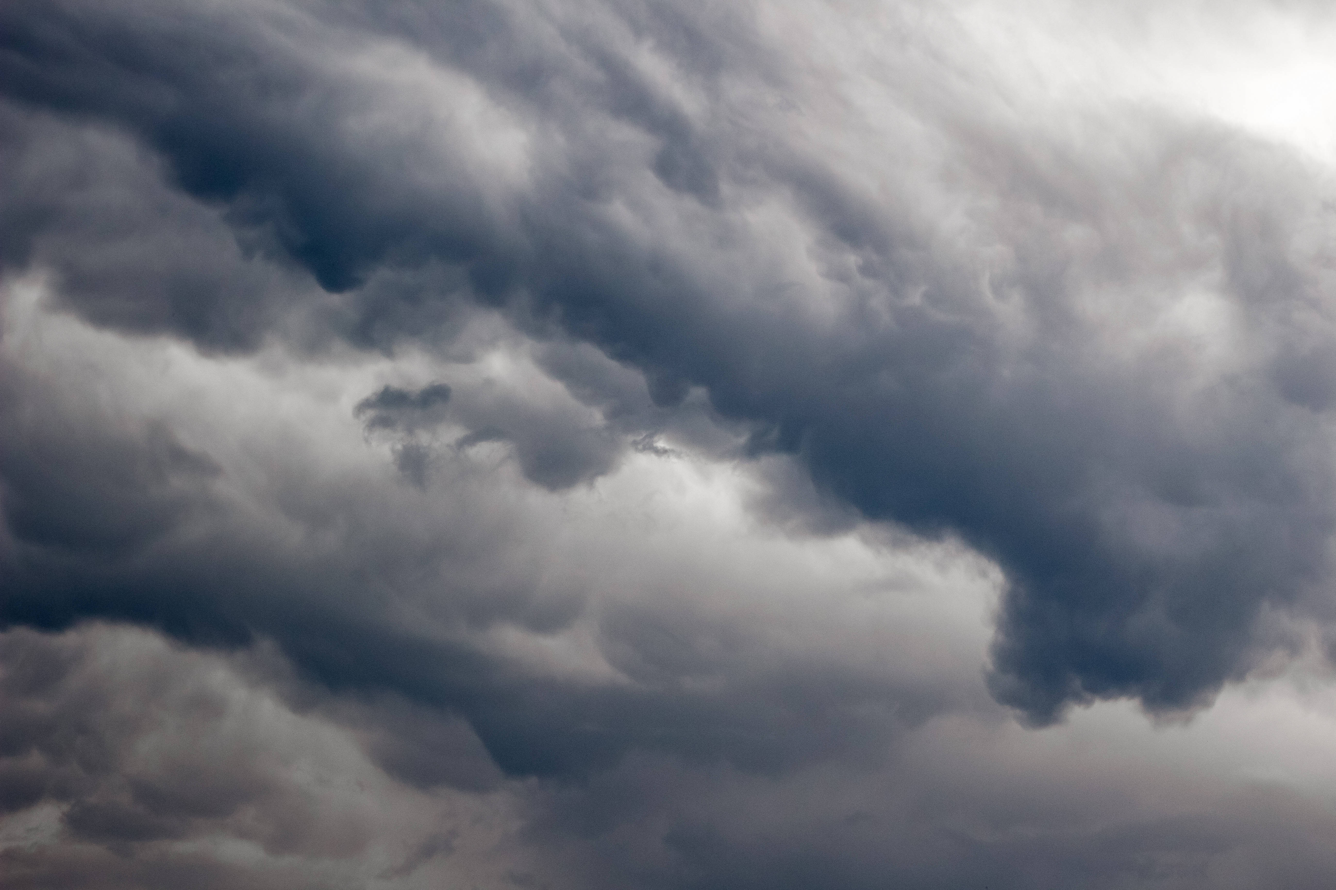 簡約暗黑風格烏雲 壁紙 — 戲劇性的黑暗風暴雲層帶著不祥的灰色和白色色調在陰沉的天空中旋轉。