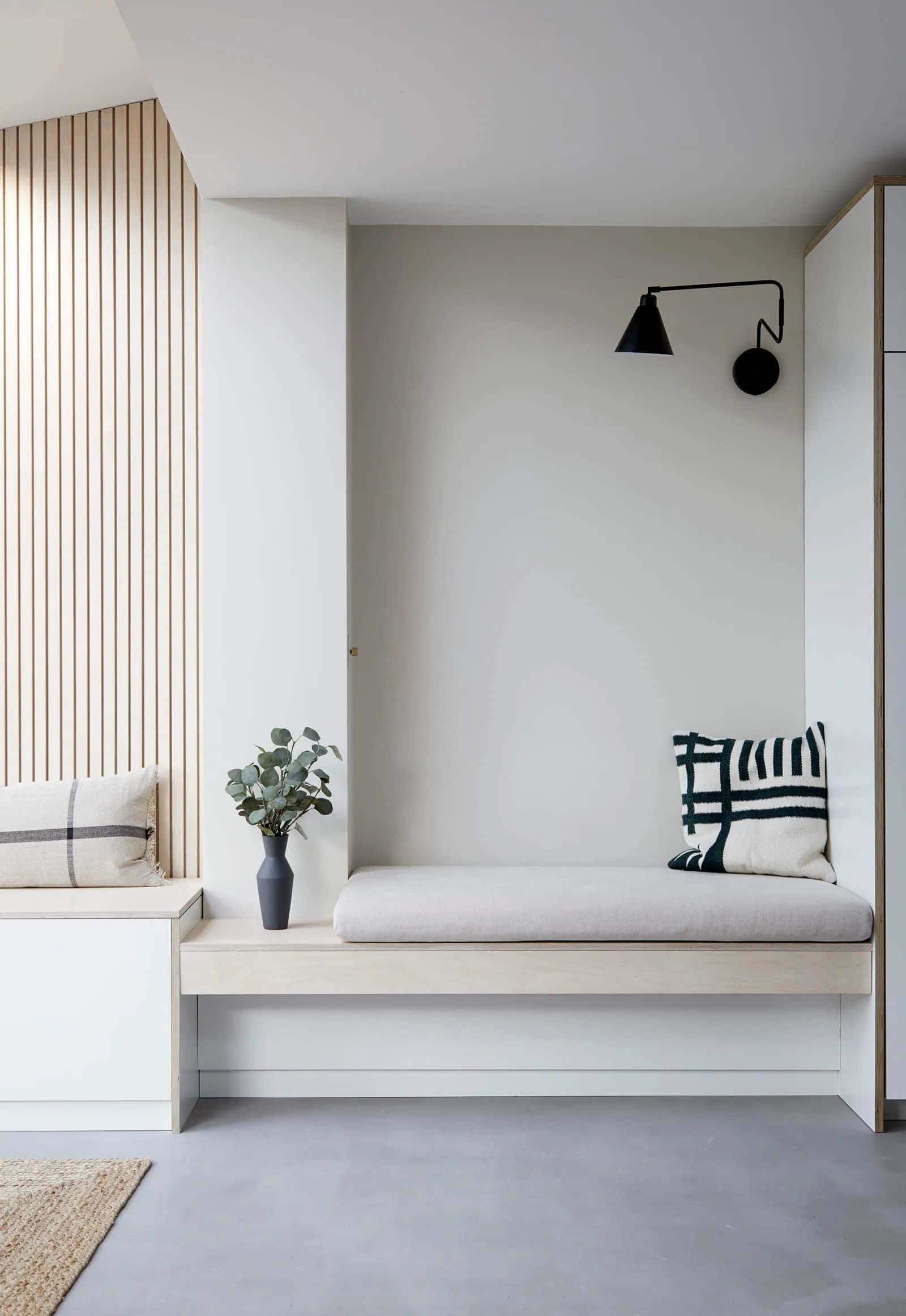 Minimalist Design 桌布 壁紙 — 簡約現代室內設計，淺色木長凳、黑色壁燈和中性牆上的圖案靠墊。