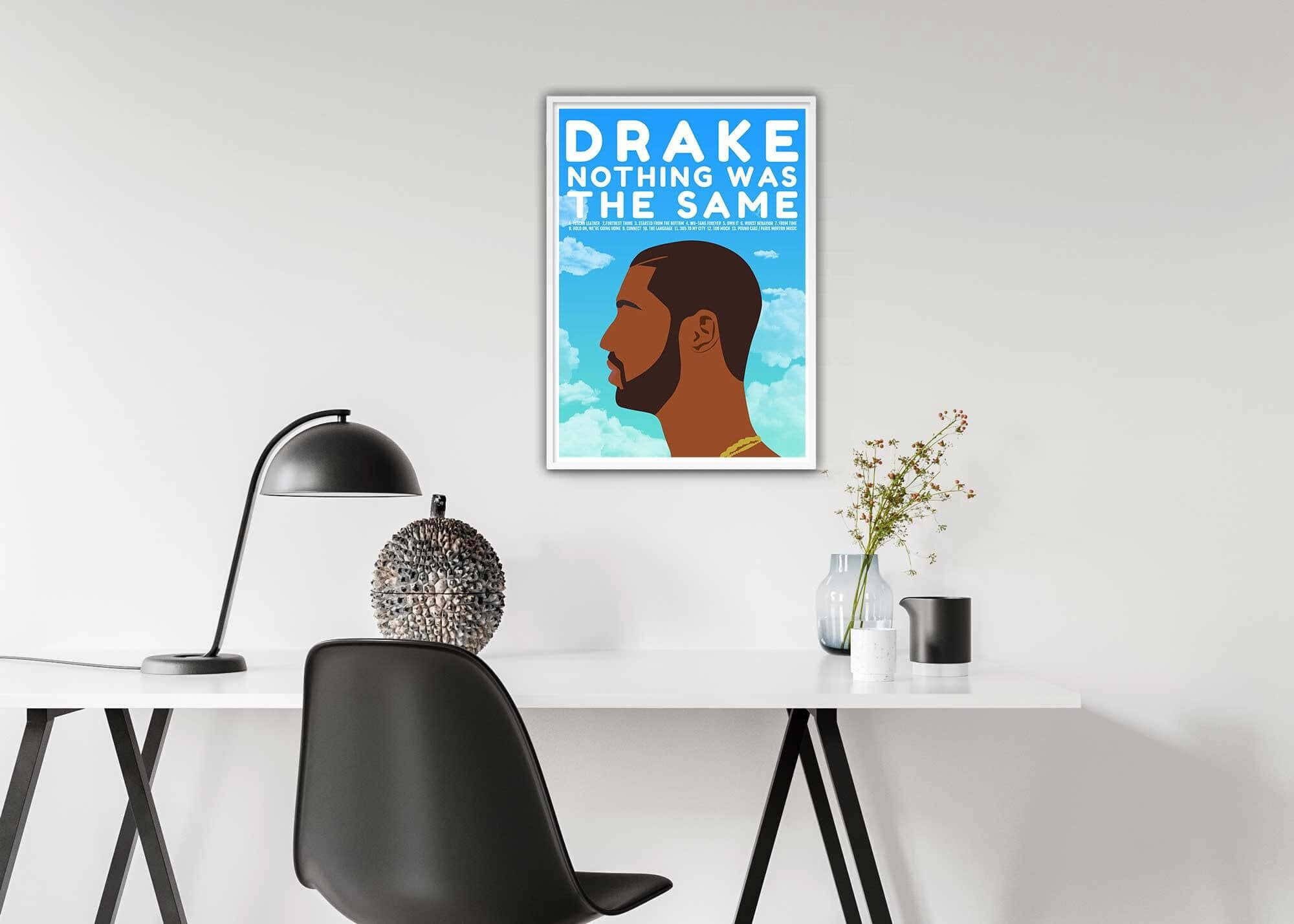 Drake - 《Nothing Was The Same》 壁紙 — 簡約現代辦公桌設置，牆上掛著Drake專輯海報框，下方是時尚黑色椅子和燈。