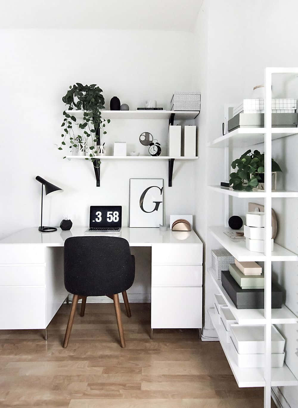 Minimalist Design 桌布 壁紙 — 簡約白色家居辦公室，配備時尚書桌、黑色椅子、木地板，以及放置植物、書籍和裝飾品的浮動層架。