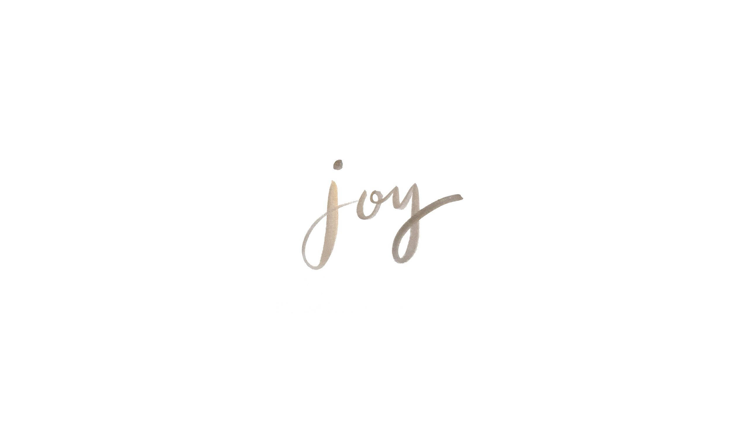 簡約白色快樂 壁紙 — 「joy」這個詞以柔和的金色草書優雅地書寫在潔白的背景上。