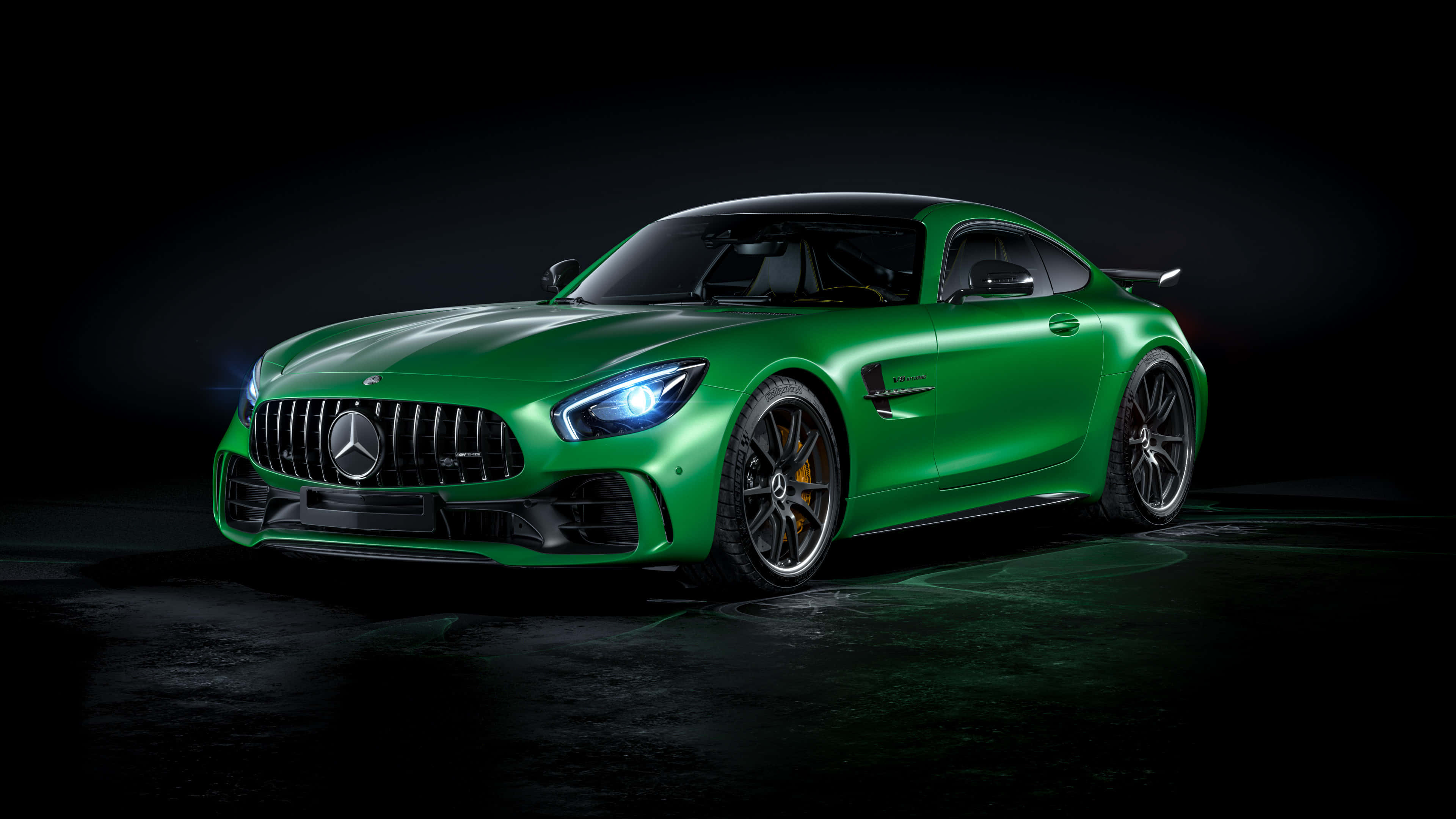 簡約綠色梅賽德斯-AMG GT R 背景 壁紙 — 一輛充滿活力的綠色Mercedes-AMG GT R跑車在攝影棚燈光下閃閃發光，背景為深色。