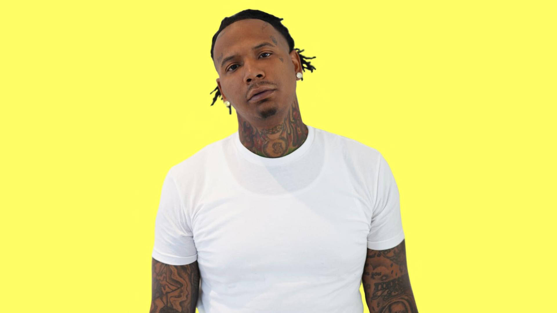 簡約風格的 Moneybagg Yo 壁紙 — 一個有紋身和辮子髮型的男人，在明亮的黃色背景前嚴肅地凝視。