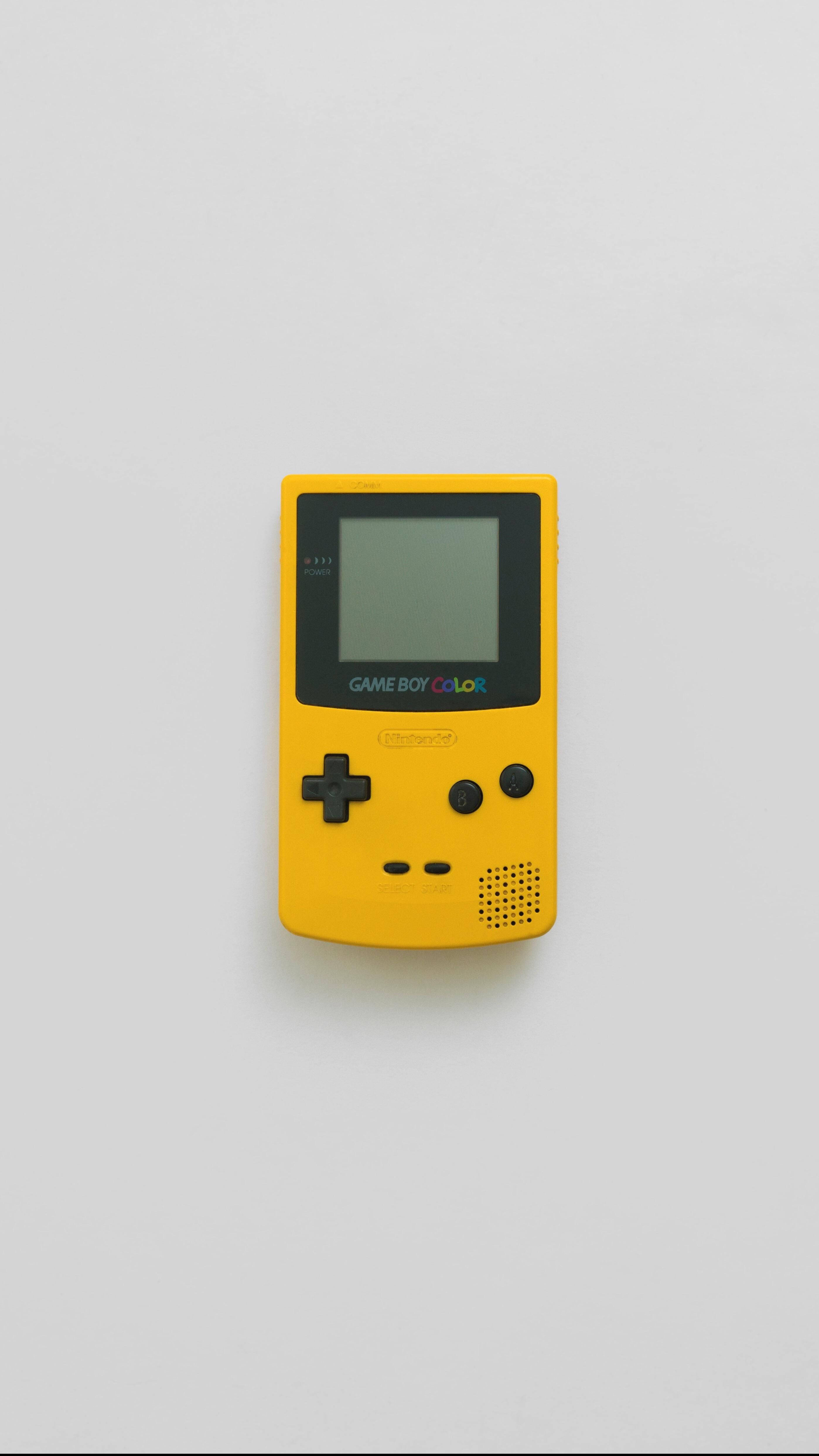 簡約黃色Game Boy Color 壁紙 — 一部亮黃色的 Game Boy Color 主機置於純白表面中央，光線柔和均勻。