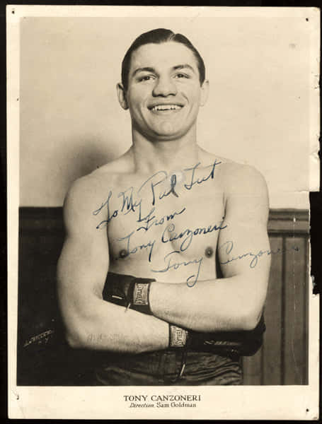赤裸上身的拳擊手Tony Canzoneri微笑交叉雙臂、胸前有簽名。