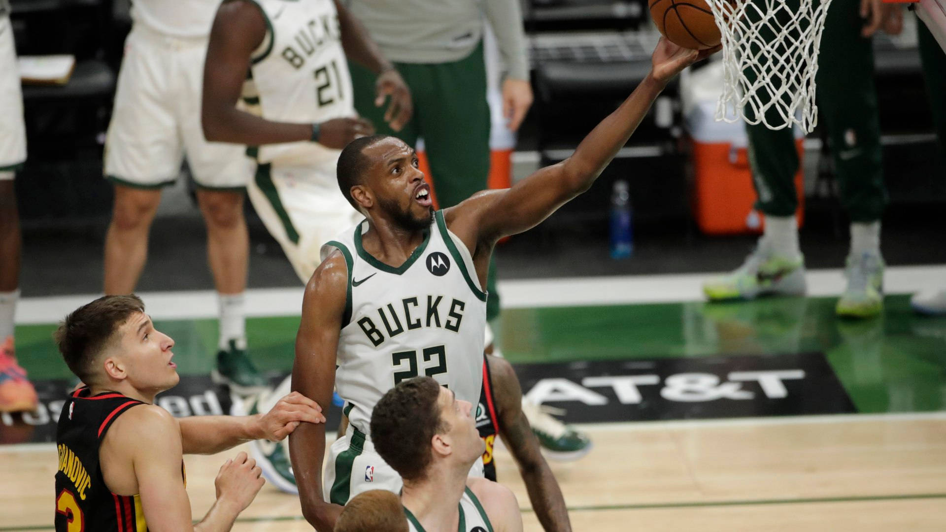籃球員 Khris Middleton 壁紙 — 一位身穿白色球衣的密爾沃基公鹿隊球員在硬木球場上入樽，防守球員專注地觀看。