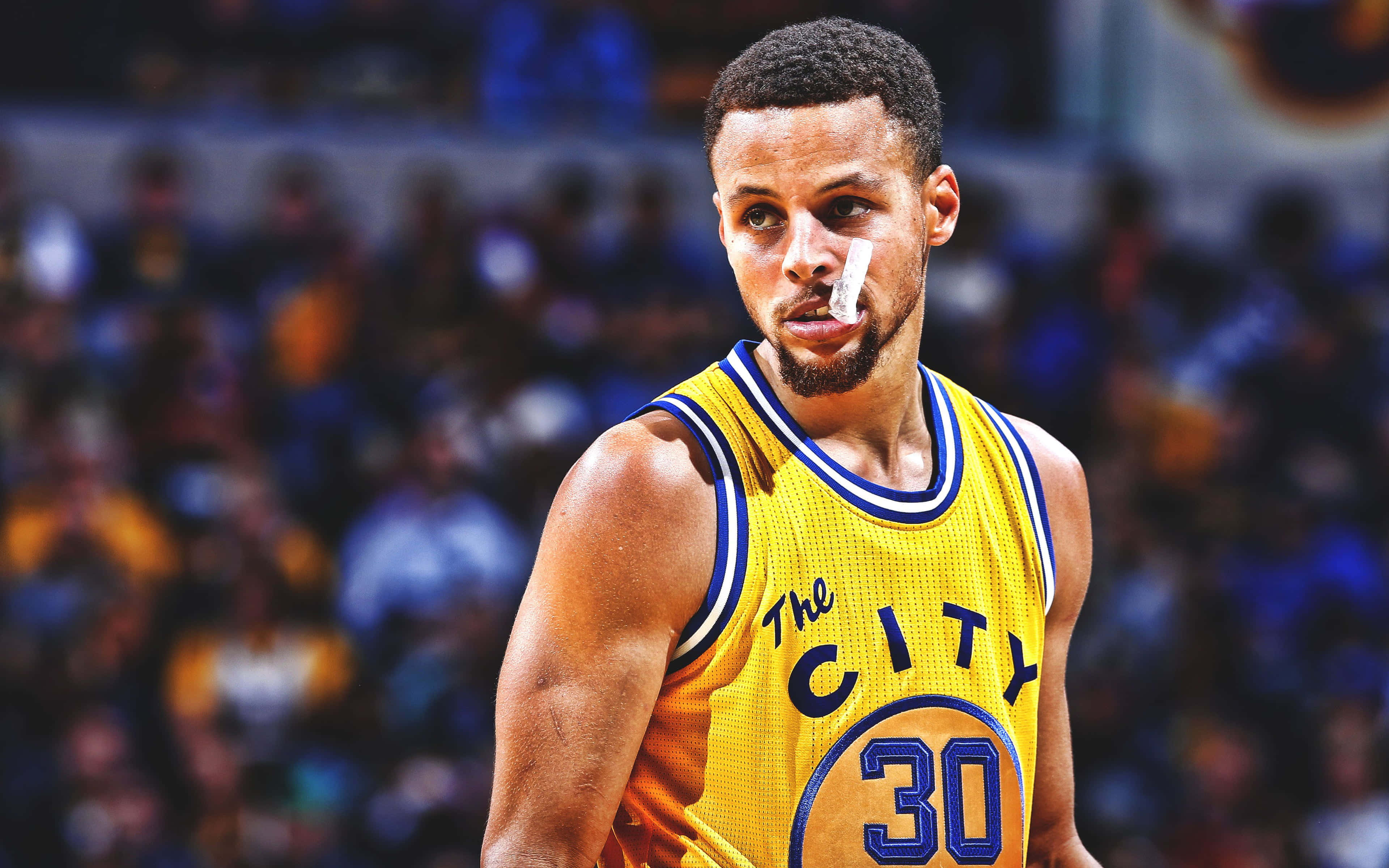 steph curry 桌布 壁紙 — 籃球運動員史提芬·居里身穿黃色金州勇士球衣，上面有'The City'和30號，在比賽中專注地凝視，背景是模糊的人群。
