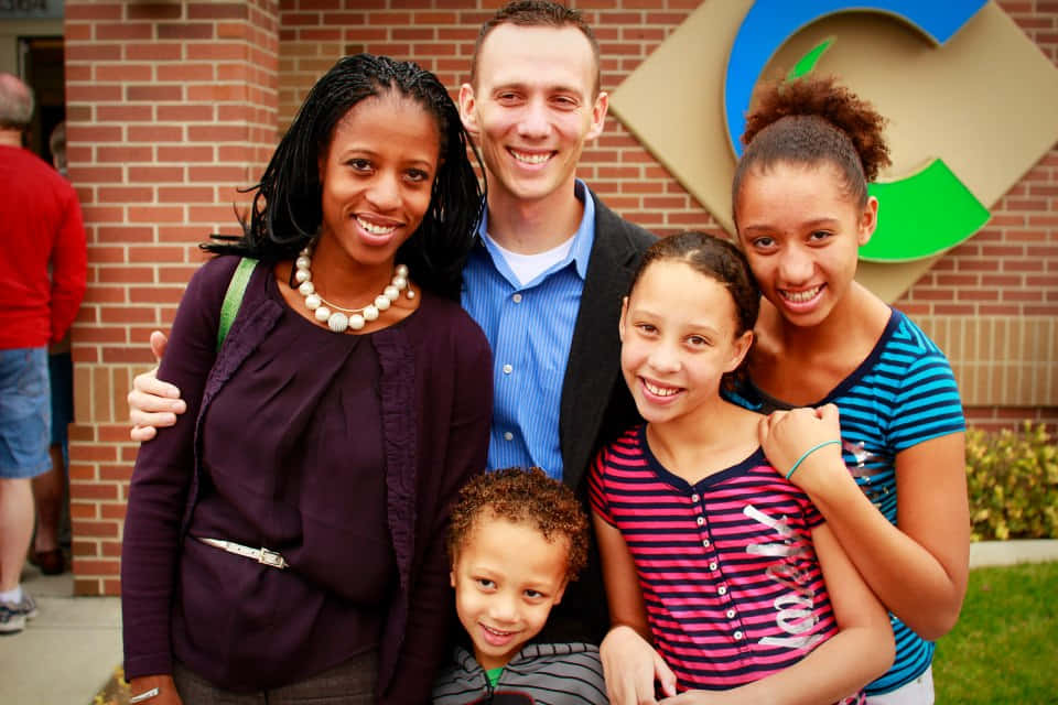 一個幸福的五人家庭在校舍外微笑拍照。