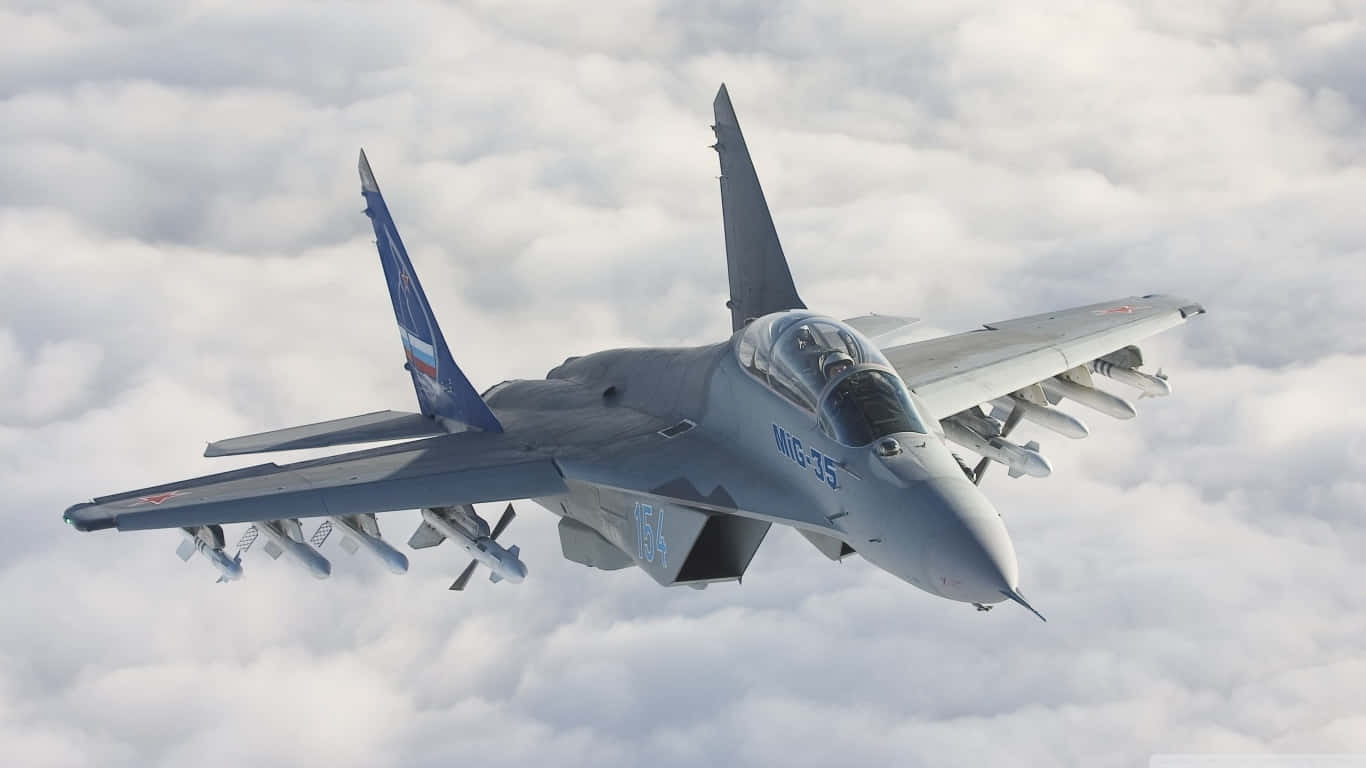 米格-35 飛越雲層的巨型客機背景（1366x768） 壁紙 — 一架灰色 MiG-35 戰鬥機在蓬鬆的白雲上方翱翔，武器和駕駛艙清晰可見。