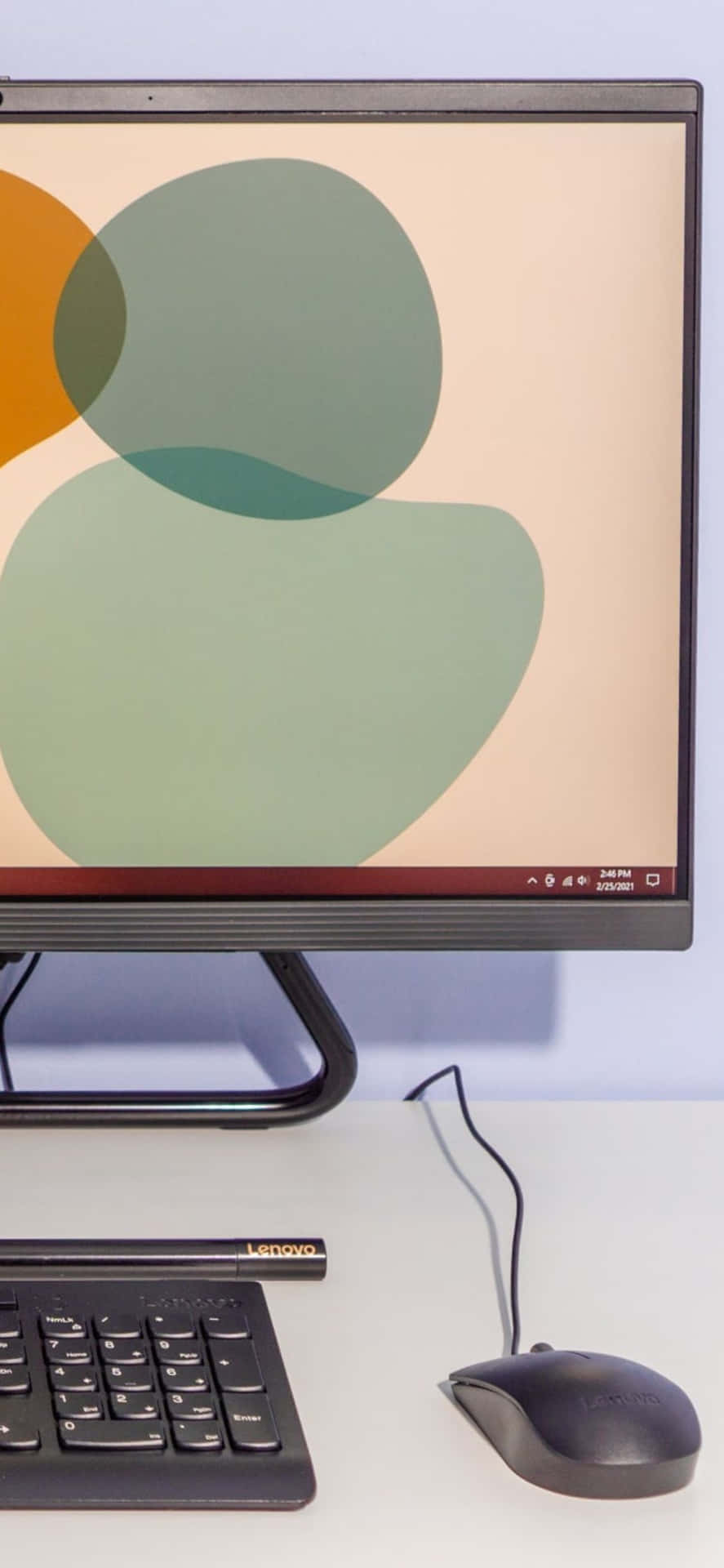 黑色 Lenovo 一體式電腦，白色桌子上帶有抽象壁紙。