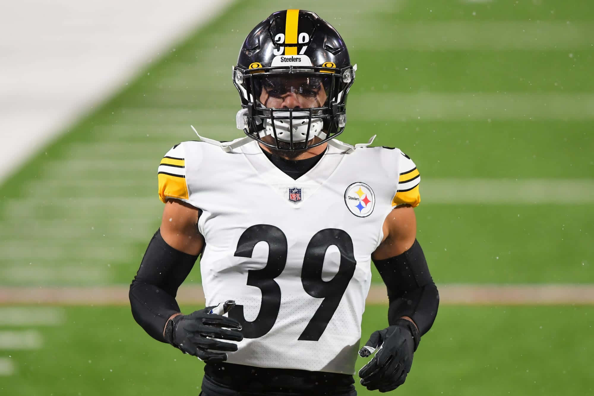 米納卡·菲茨帕特里克匹茲堡鋼人隊NFL 壁紙 — 一名身穿白色和黃色球衣的匹茲堡鋼人隊美式足球員在體育場燈光下的綠色球場上奔跑。