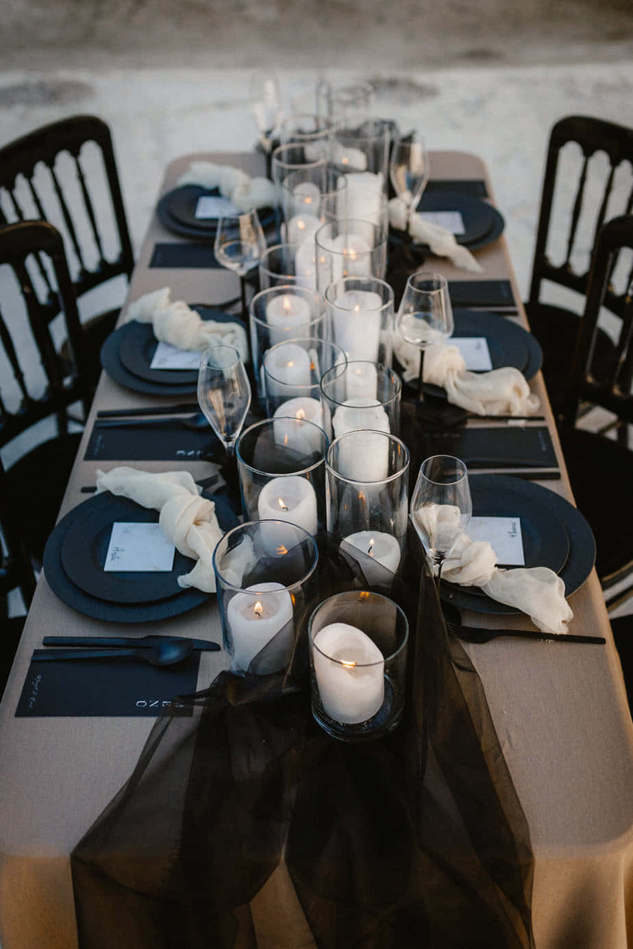 Black And White Wedding 桌布 壁紙 — 米色枱布上帶有玻璃燭台內點燃蠟燭的優雅黑白餐桌佈置。