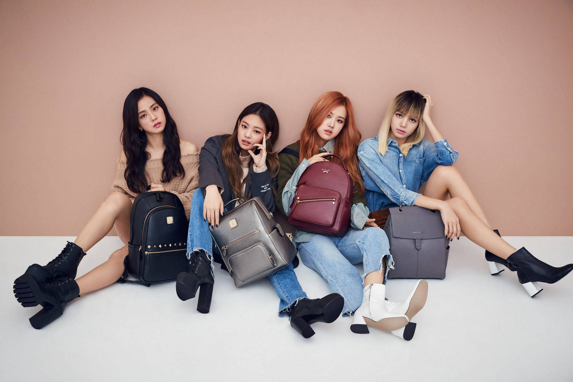 米色牆壁 Blackpink 桌面壁紙 壁紙 — 四位時尚女性在白色地板上，以柔和的粉紅色牆壁為背景，隨意地擺姿勢，背著設計師背包。