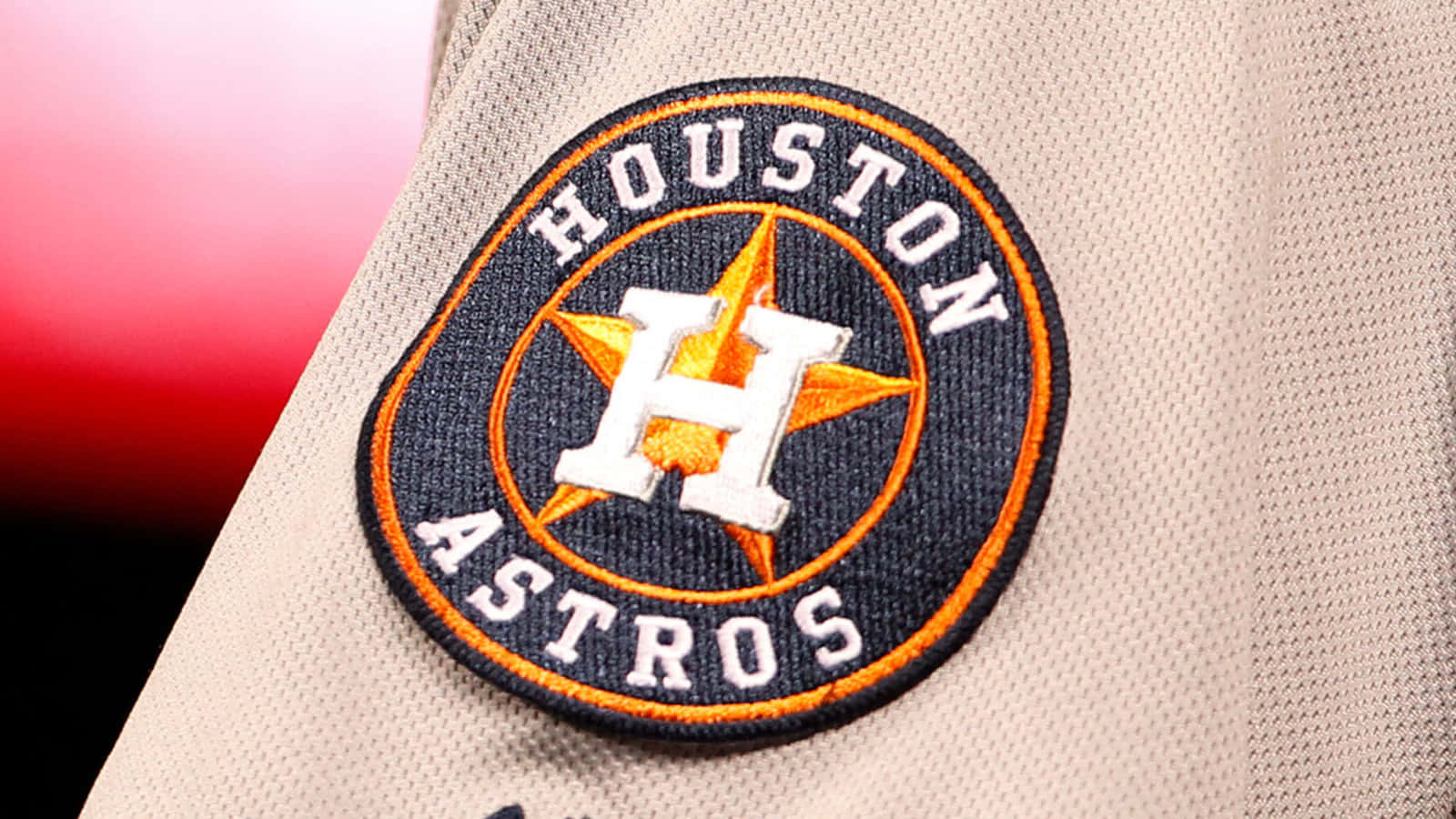 Astros 桌布 壁紙 — 米色球衣袖子上休斯頓太空人棒球隊徽章的近距離特寫，帶有橙色和海軍藍色細節。